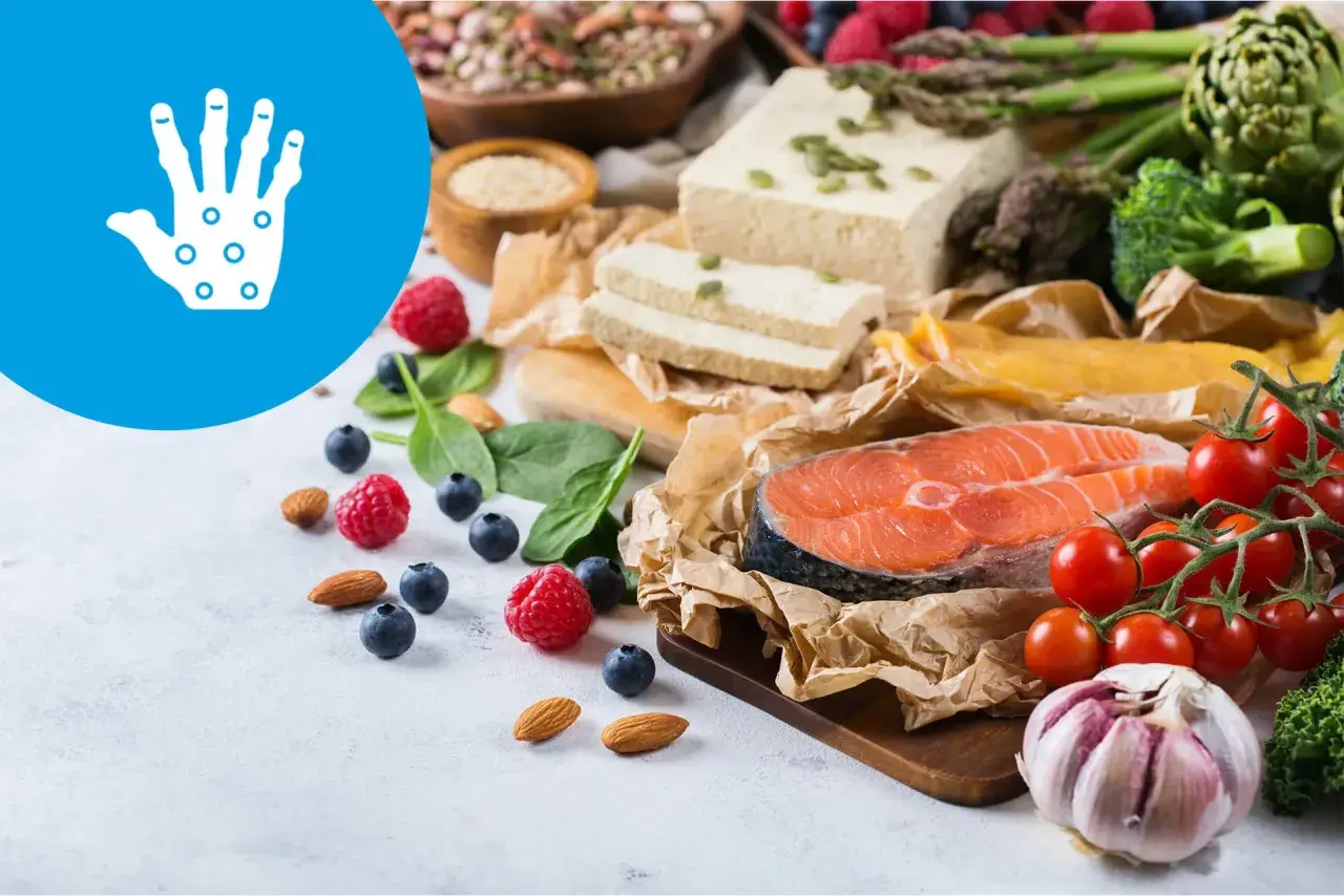 Zdrowa dieta przy łuszczycy: łosoś, warzywa, owoce, orzechy i tofu. Ikona dłoni symbolizuje problemy skórne.