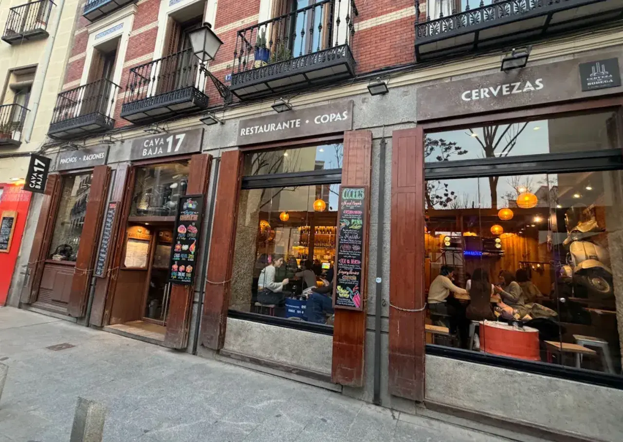 Fachada del restaurante Cava Baja 17, con gente dentro disfrutando de tapas y copas.