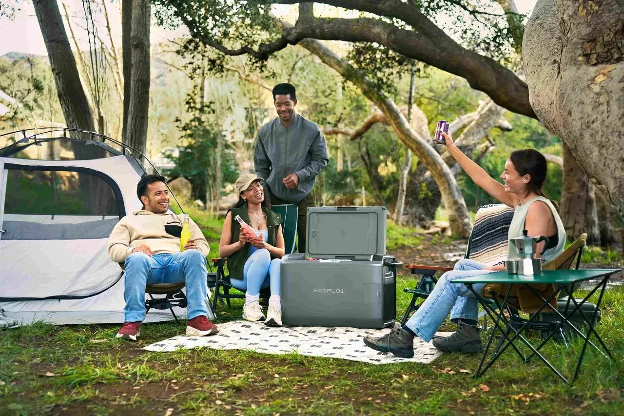 Amis profitant d'un camping chez l'habitant en France, avec tente, glacière et boissons.