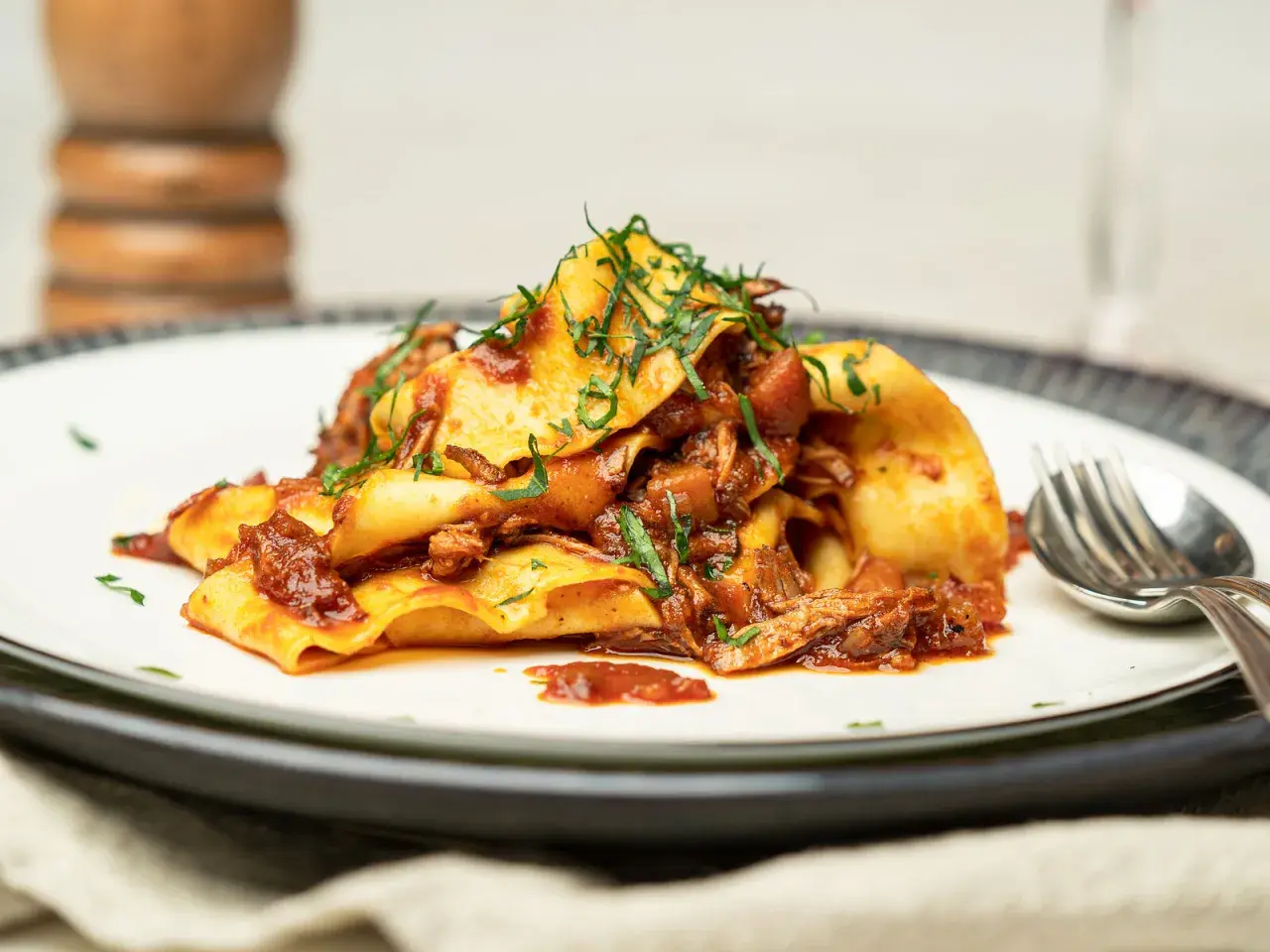 Herzhaftes Pasta Ragu mit breiten Nudeln, übergossen mit einer reichhaltigen Fleischsauce und garniert mit frischen Kräutern.
