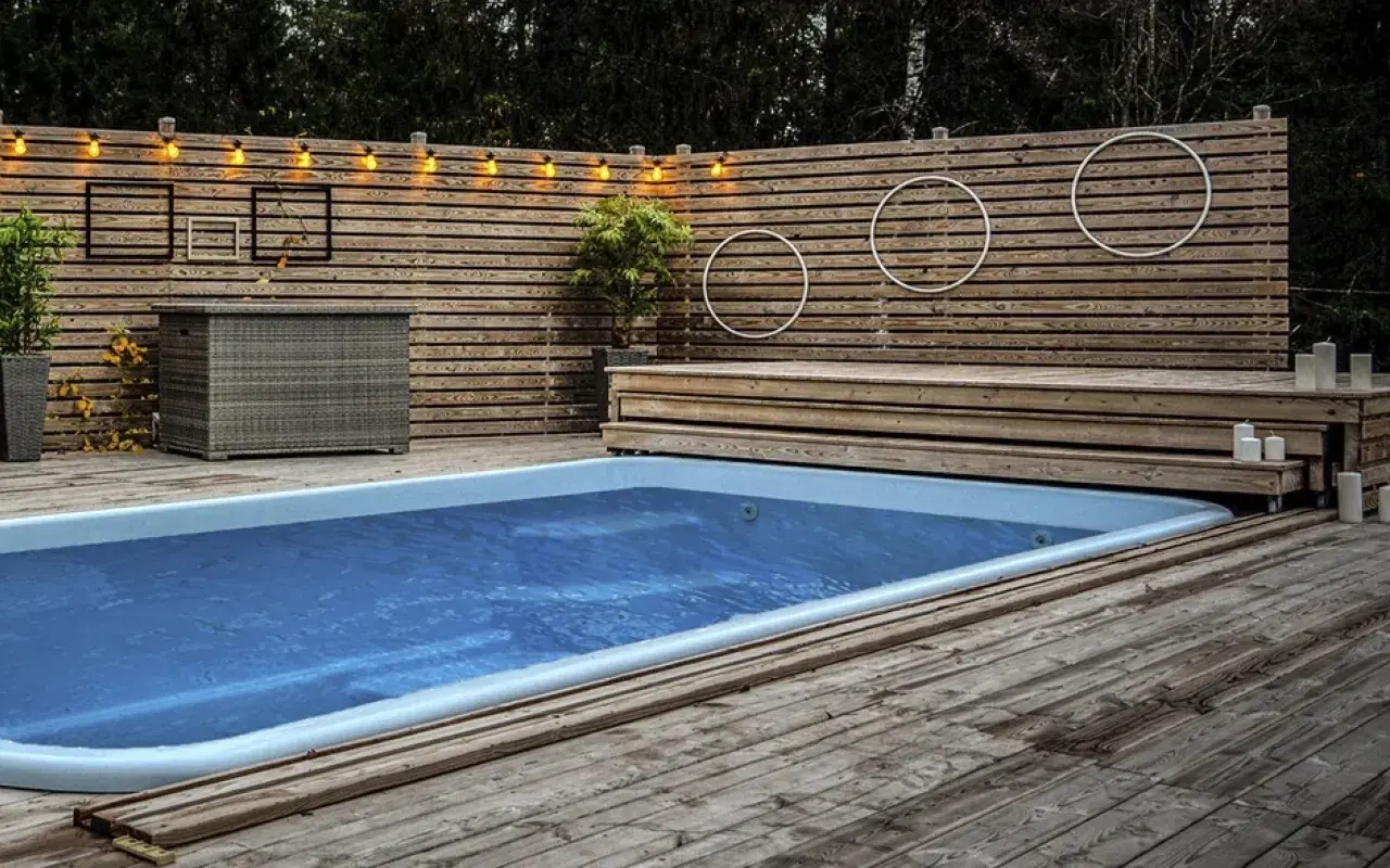 En avkopplande oas med en pool omgiven av en vacker trall. Ljusslingor och dekorationer skapar en mysig atmosfär.