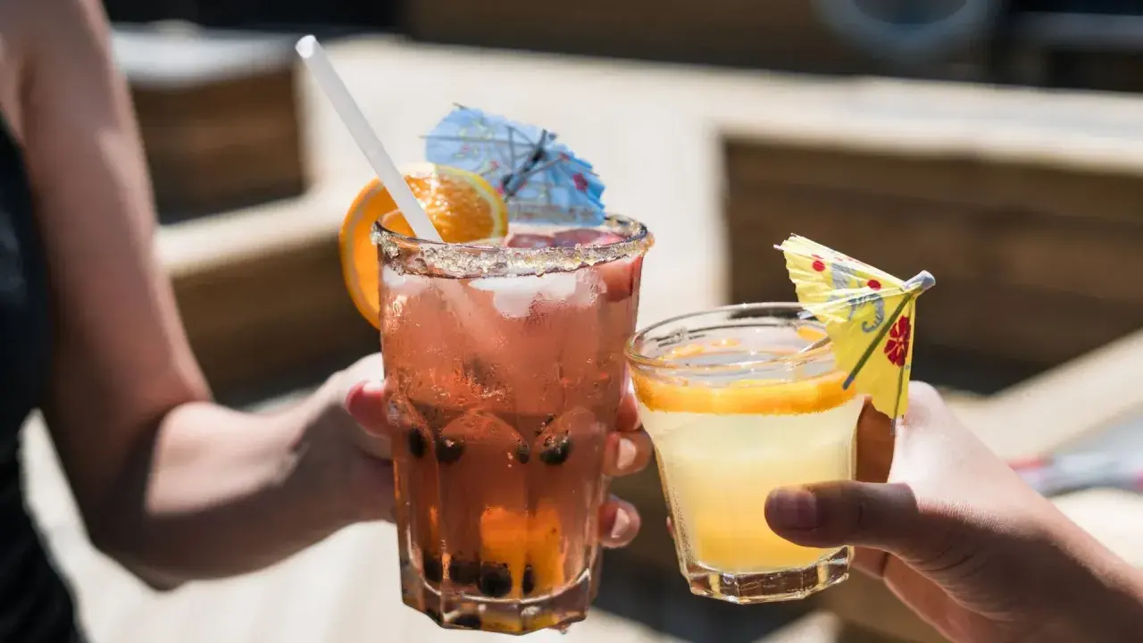 Dwa orzeźwiające drinki, jeden różowy z owocami i pomarańczą, drugi żółty z plasterkiem cytrusa. Idealne na letnie popołudnie, może z dodatkiem białego wina.