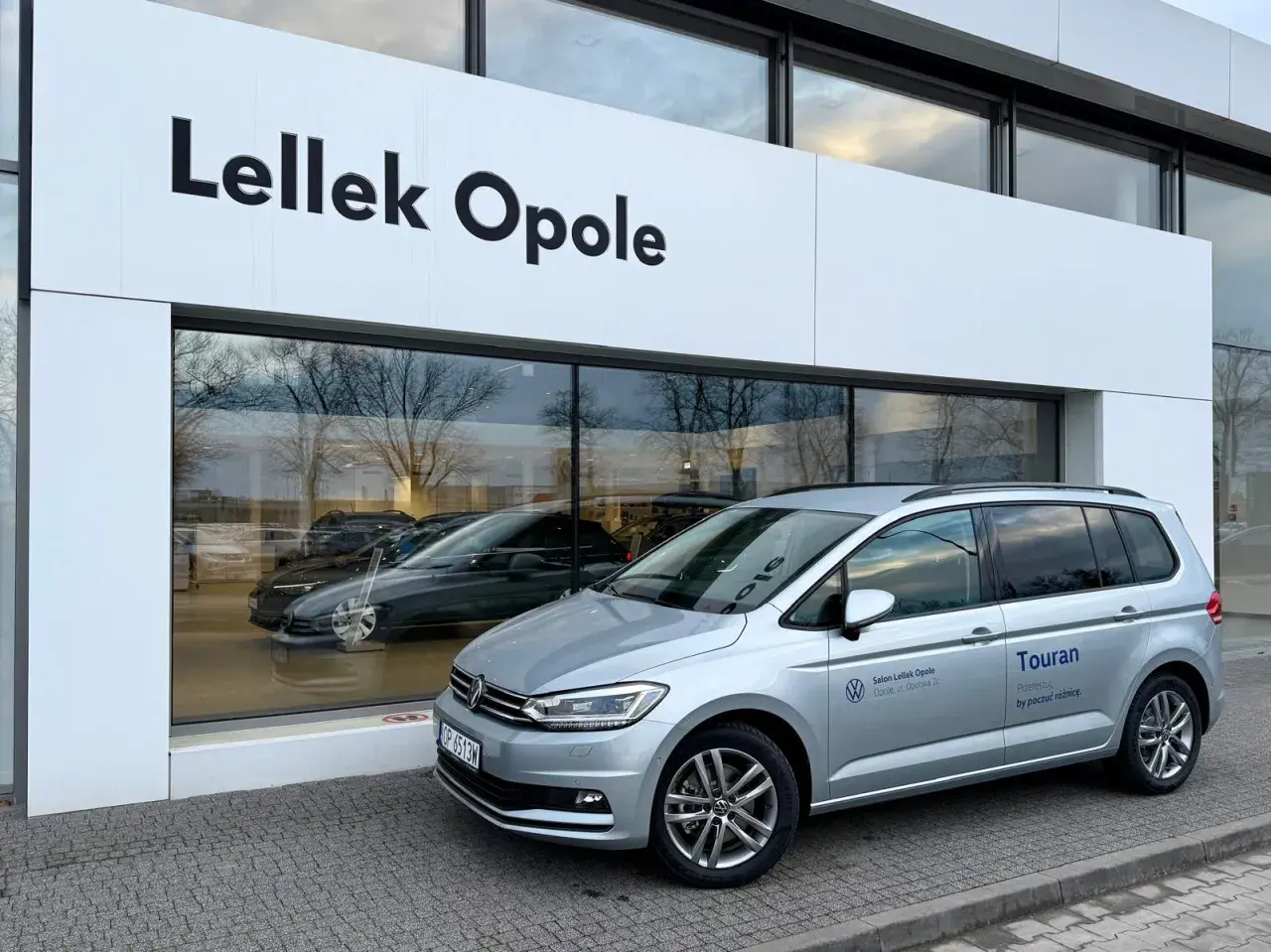 Srebrny Volkswagen Touran przed salonem Lellek Opole.