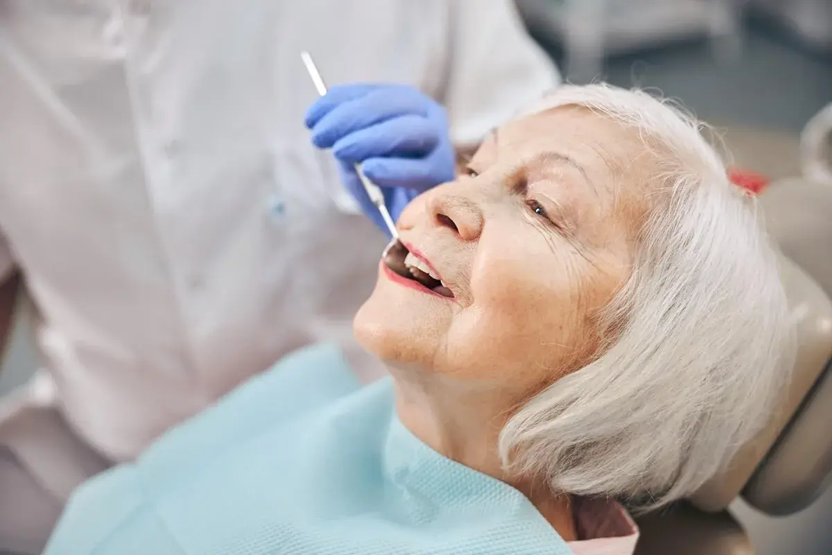 Starsza pani u dentysty, która właśnie otrzymała protezę akronową.
