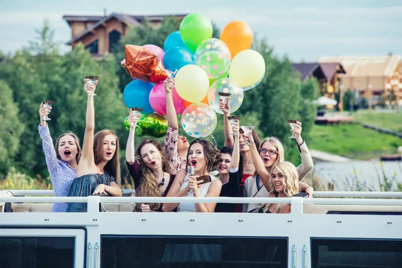Radosne kobiety z kieliszkami i balonami świętują wieczór panieński.