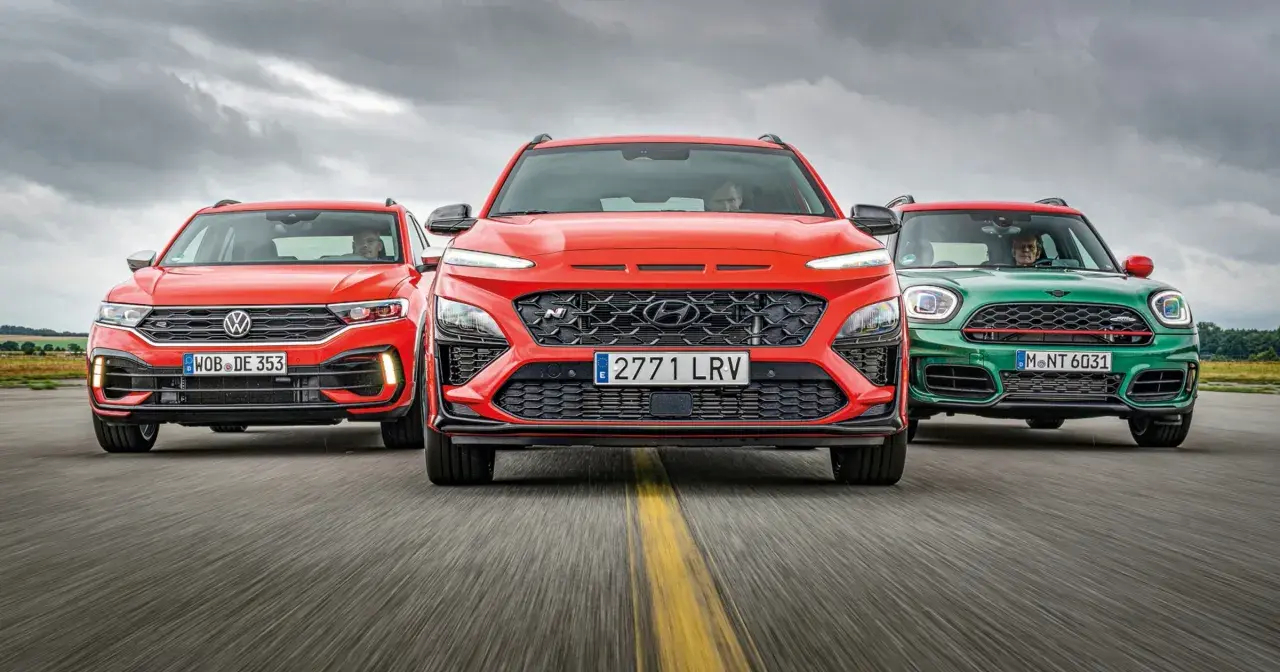 Trzy sportowe małe SUV-y: czerwony Volkswagen, pomarańczowy Hyundai i zielony Mini, jadące po drodze.