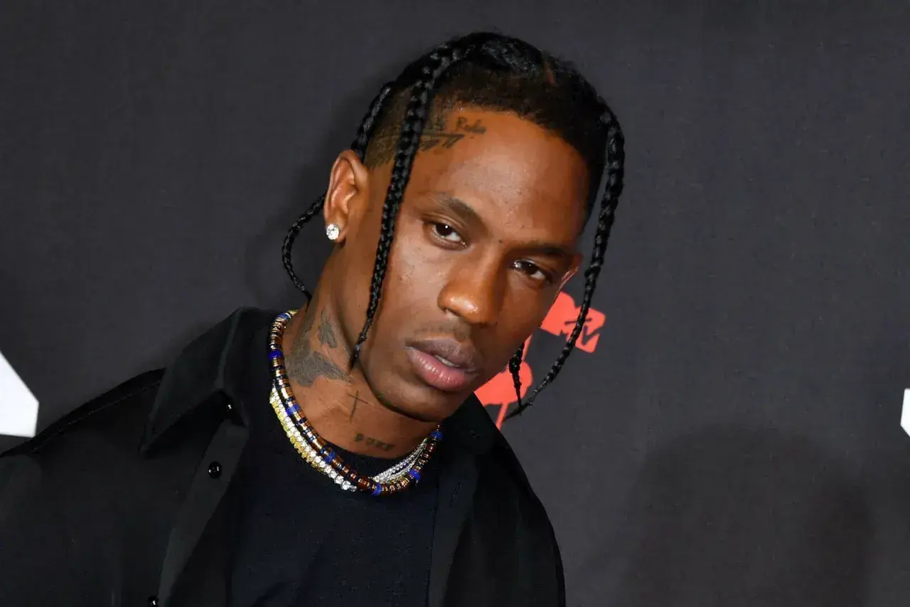 Travis Scott w czarnej koszuli i naszyjnikach, z warkoczami. Fani w Polsce czekają na jego koncert.