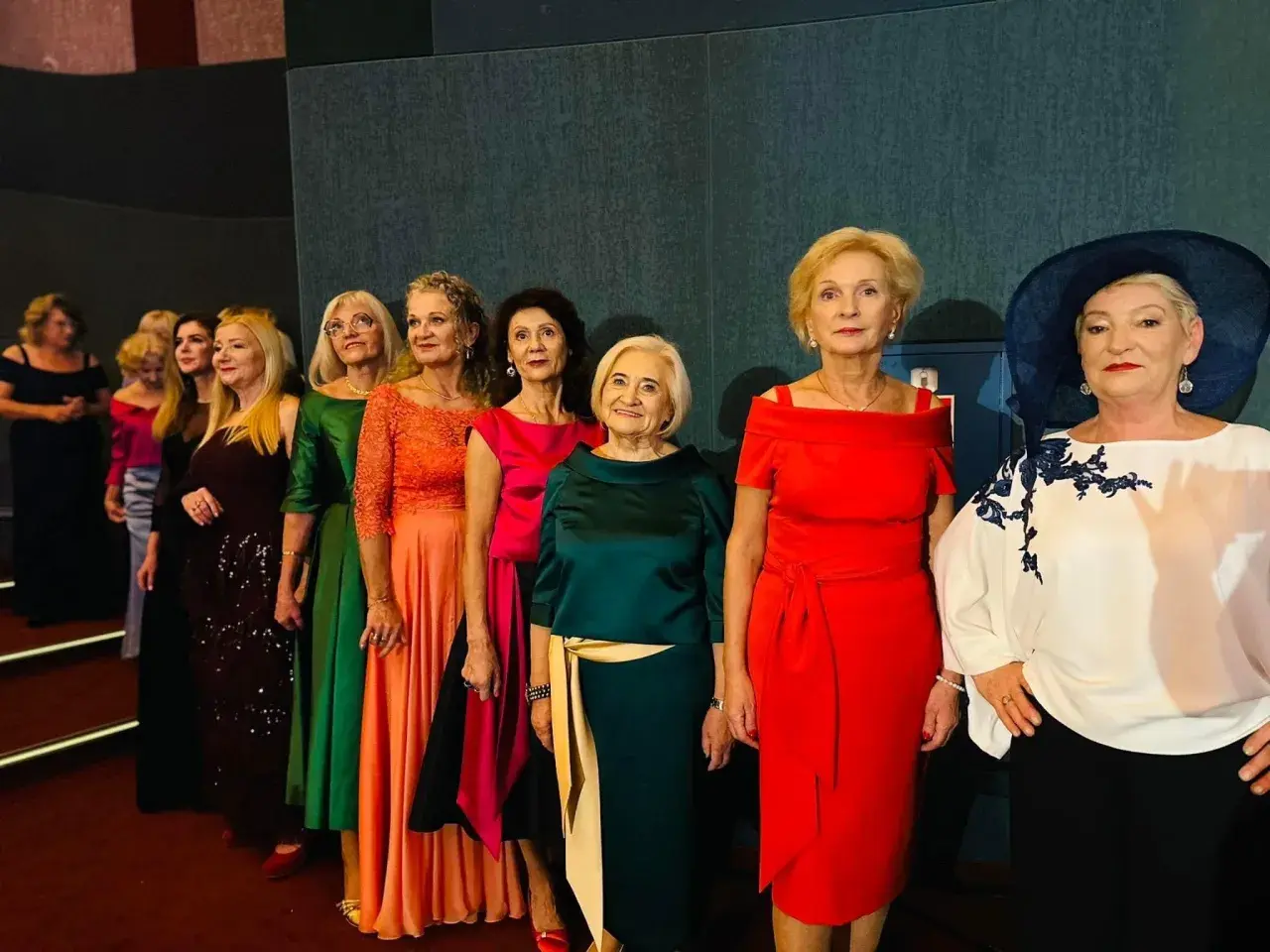 Eleganckie panie w barwnych sukniach. Jaki kolor sukienki na wesele dla mamy? Może ta ognista czerwień lub butelkowa zieleń?
