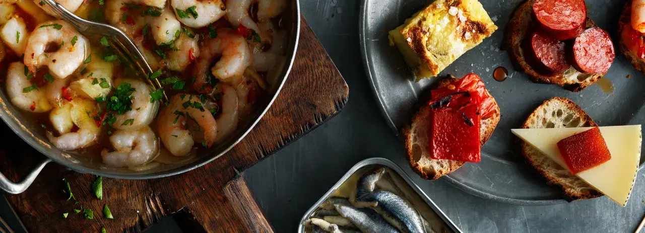 En härlig samling tapas med räkor i vitlök, sardiner och bröd med ost och paprika. Perfekt vin till tapas.