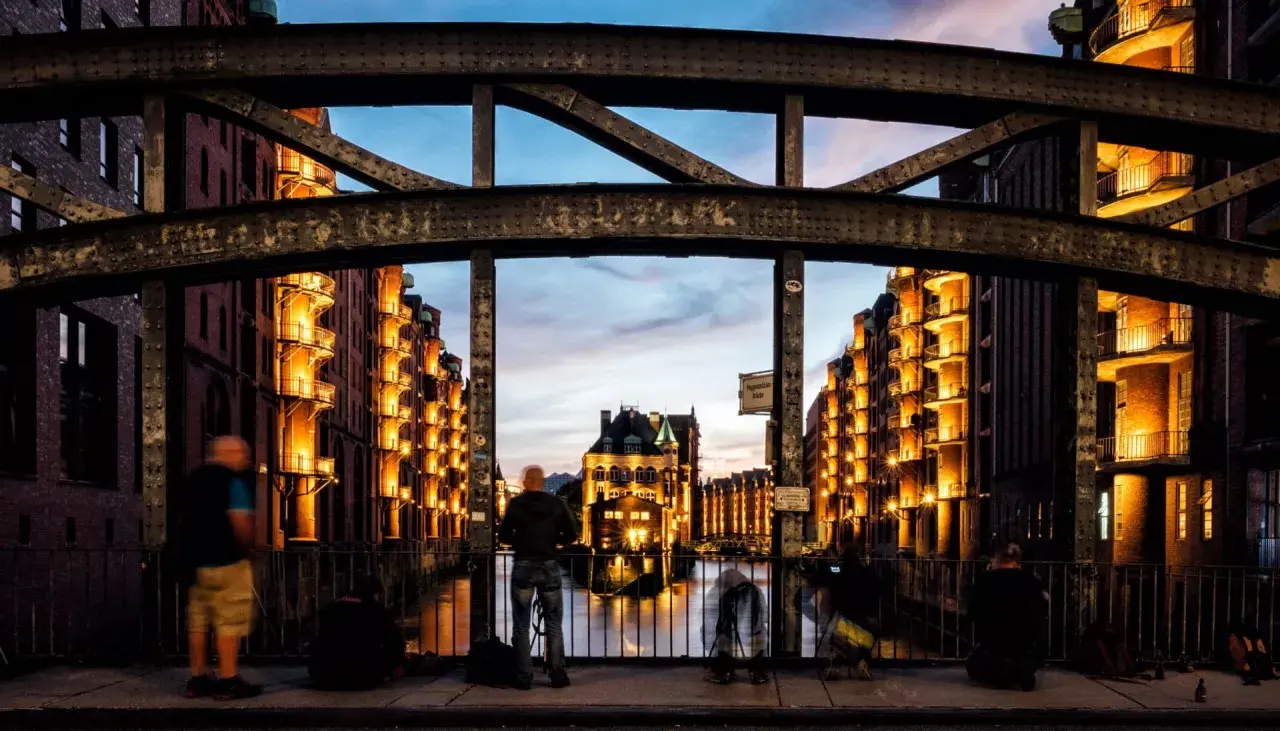 Spektakuläre Fotografie Hamburg: Speicherstadt im Abendlicht, beleuchtete Backsteingebäude spiegeln sich im Wasser.