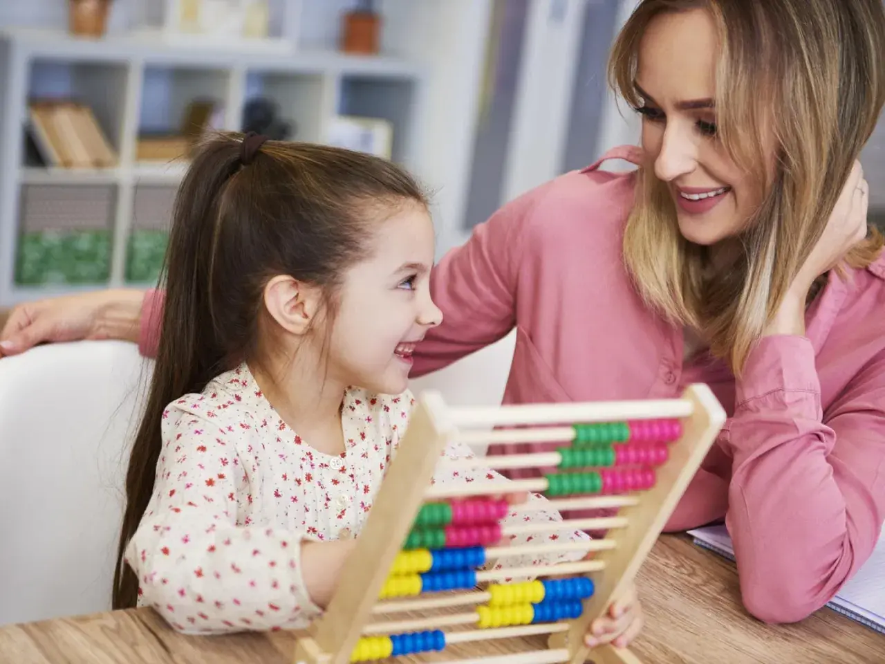 Mutter und Kind üben mit einem Abakus. Ein fröhlicher Moment vor der Einschulung, der den ersten Mathe-Test spielerisch vorbereitet.