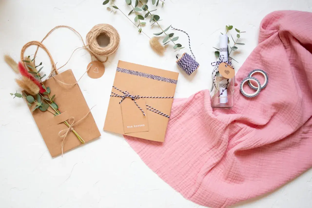 Kreatives **Gutschein verpacken** mit **Geschenkpapier** und Naturmaterialien. Eine Flasche mit Botschaft und ein kleines Päckchen warten auf ihre Übergabe.