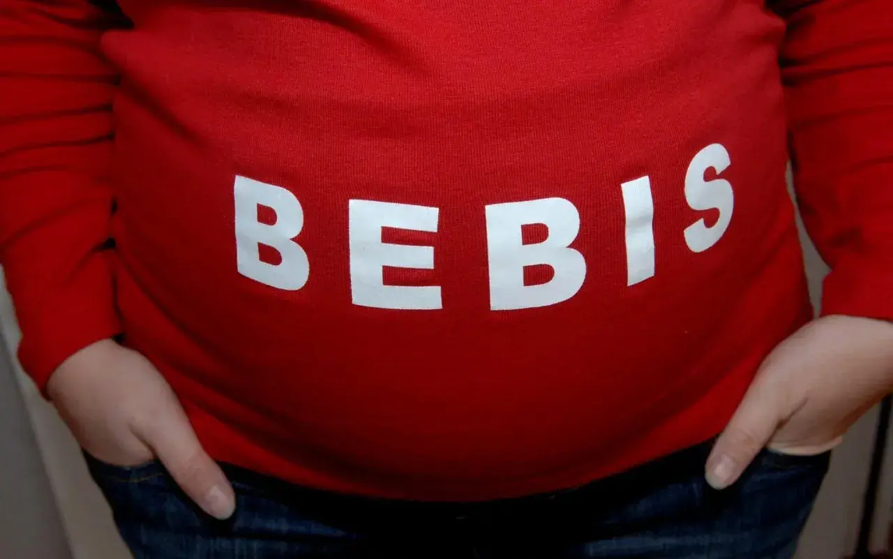 Gravid mage med texten "BEBIS". Viktigt att undvika alkohol tidig graviditet för bebisens skull.