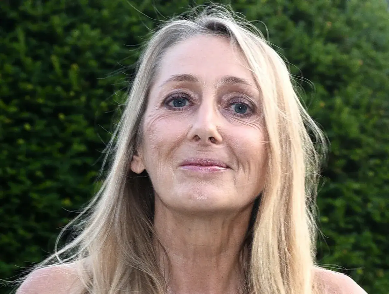 Portret Beaty Pawlikowskiej z blond włosami i niebieskimi oczami na tle zieleni.