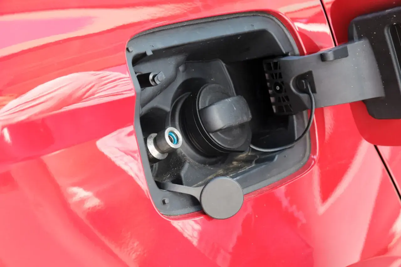 Tapa de combustible de un coche que usa GLP, con boquilla azul y tapón negro.