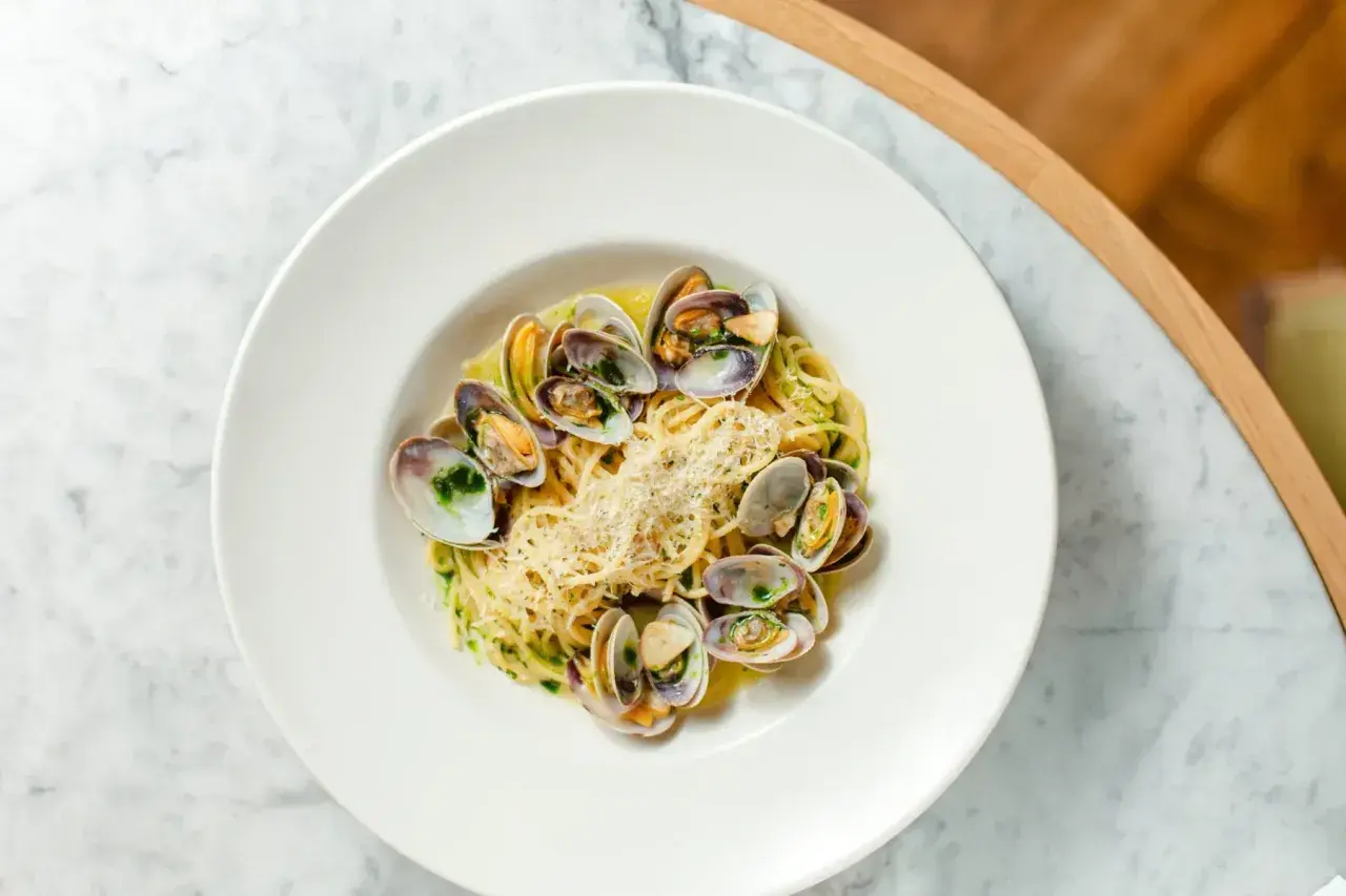 Spaghetti aux coques, une recette italienne savoureuse, garnie de parmesan râpé et d'herbes fraîches.