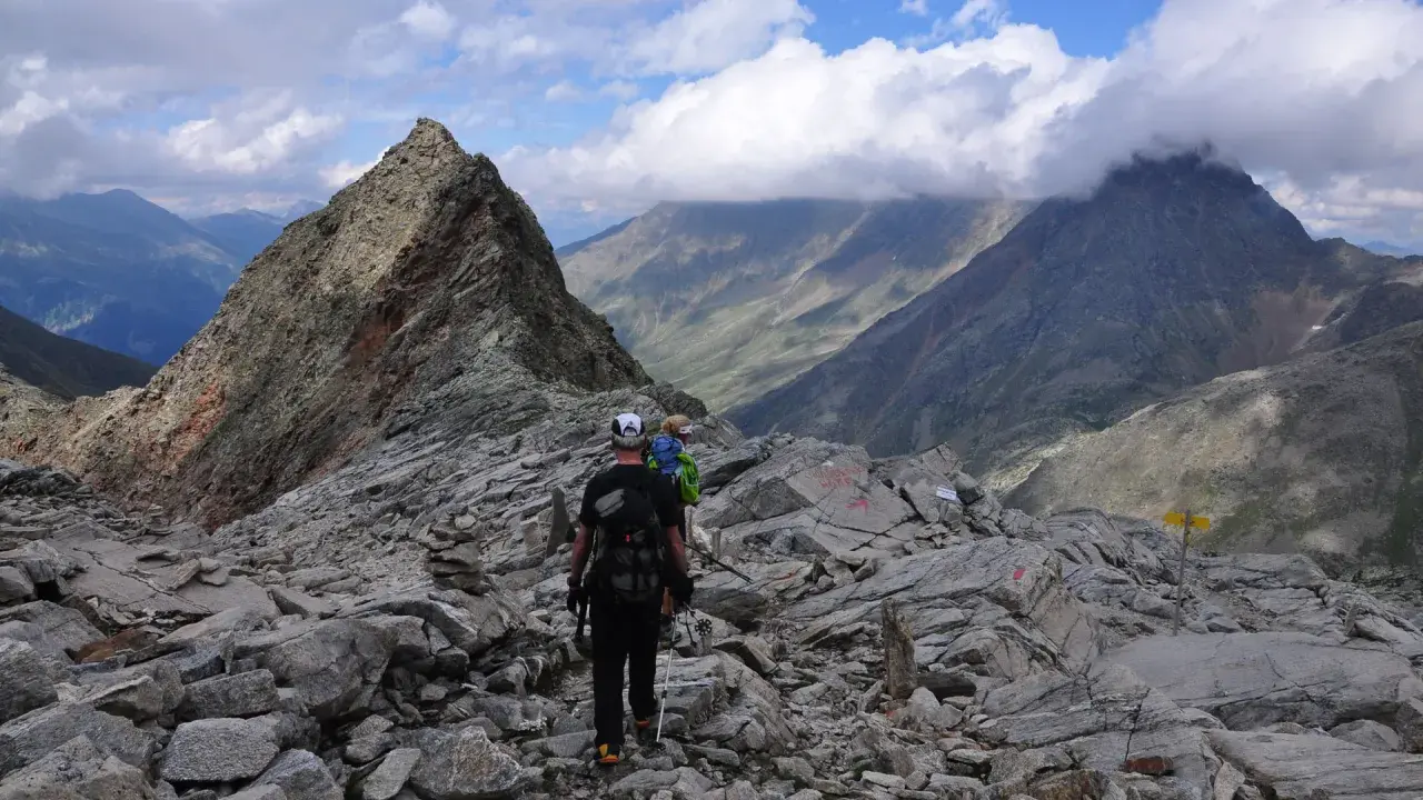 Wanderer auf einem steinigen Grat, mit Blick auf den wilden Freiger und dramatische Wolken.