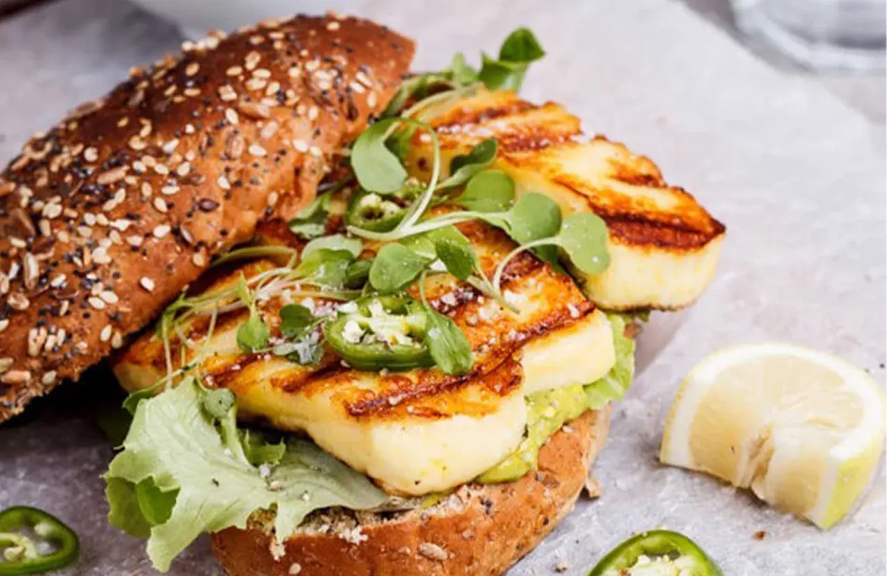 Un délicieux sandwich au halloumi grillé, garni de jalapeños et de jeunes pousses, prêt pour un barbecue estival.