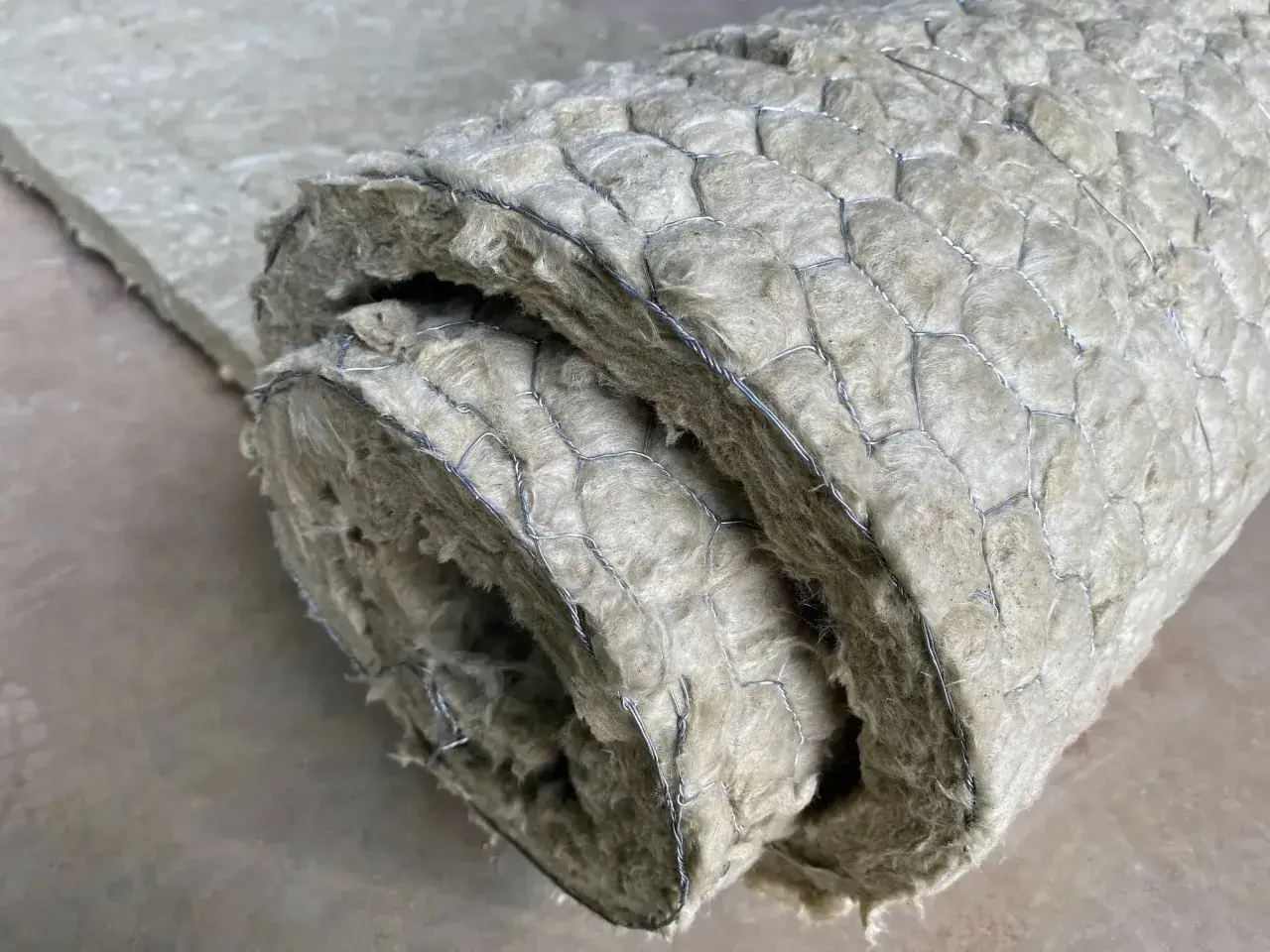 Gerolltes Dämmmaterial mit Drahtgeflecht. Um asbest erkennen zu können, ist Vorsicht geboten, da es sich um ein gesundheitsschädliches Material handelt.