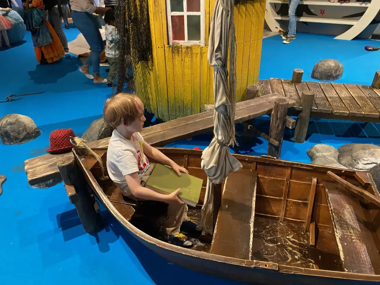 Un bambino legge un libro in una barca, un'installazione interattiva che ricorda Stoccolma con bambini.