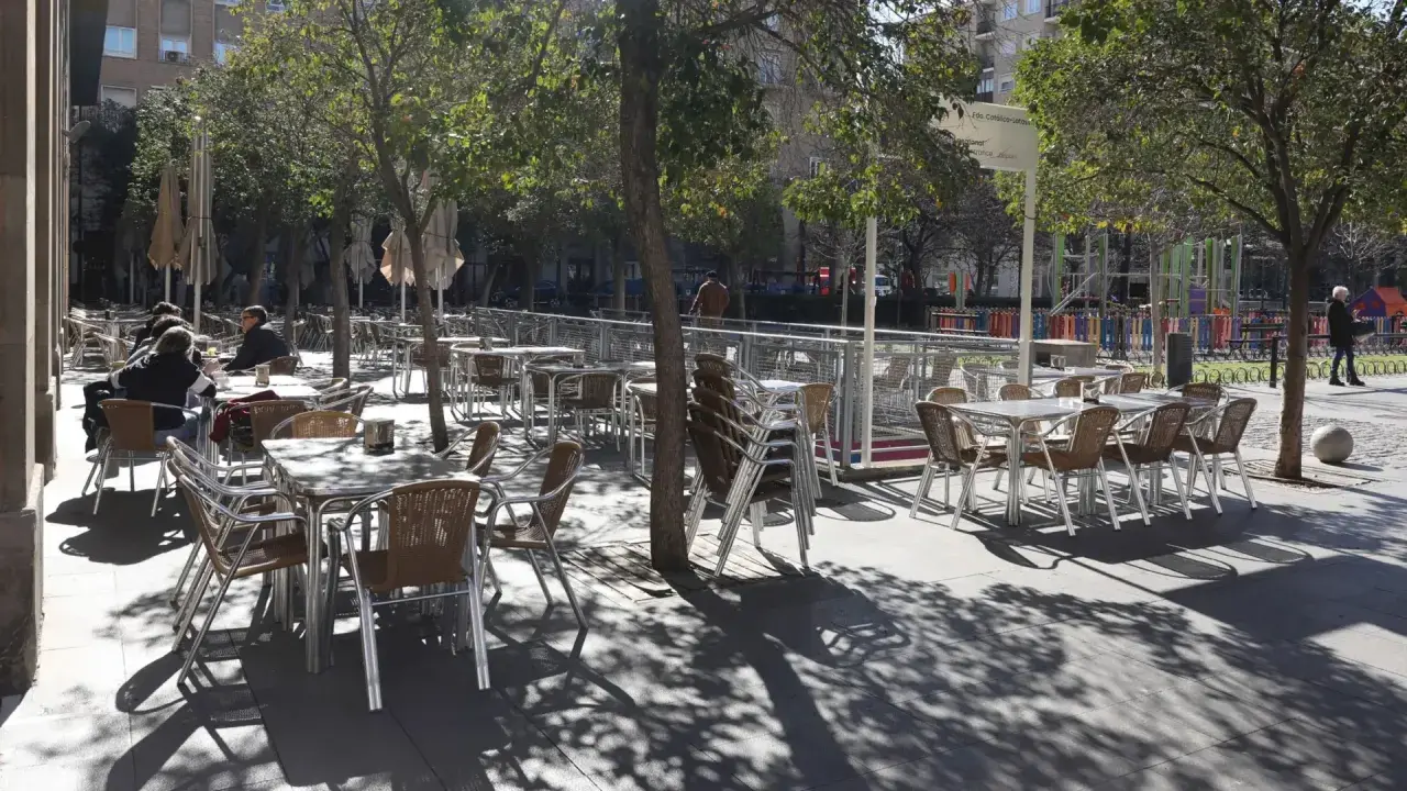 Mesas y sillas vacías en la terraza de bares de la plaza San Francisco, bajo la sombra de los árboles.