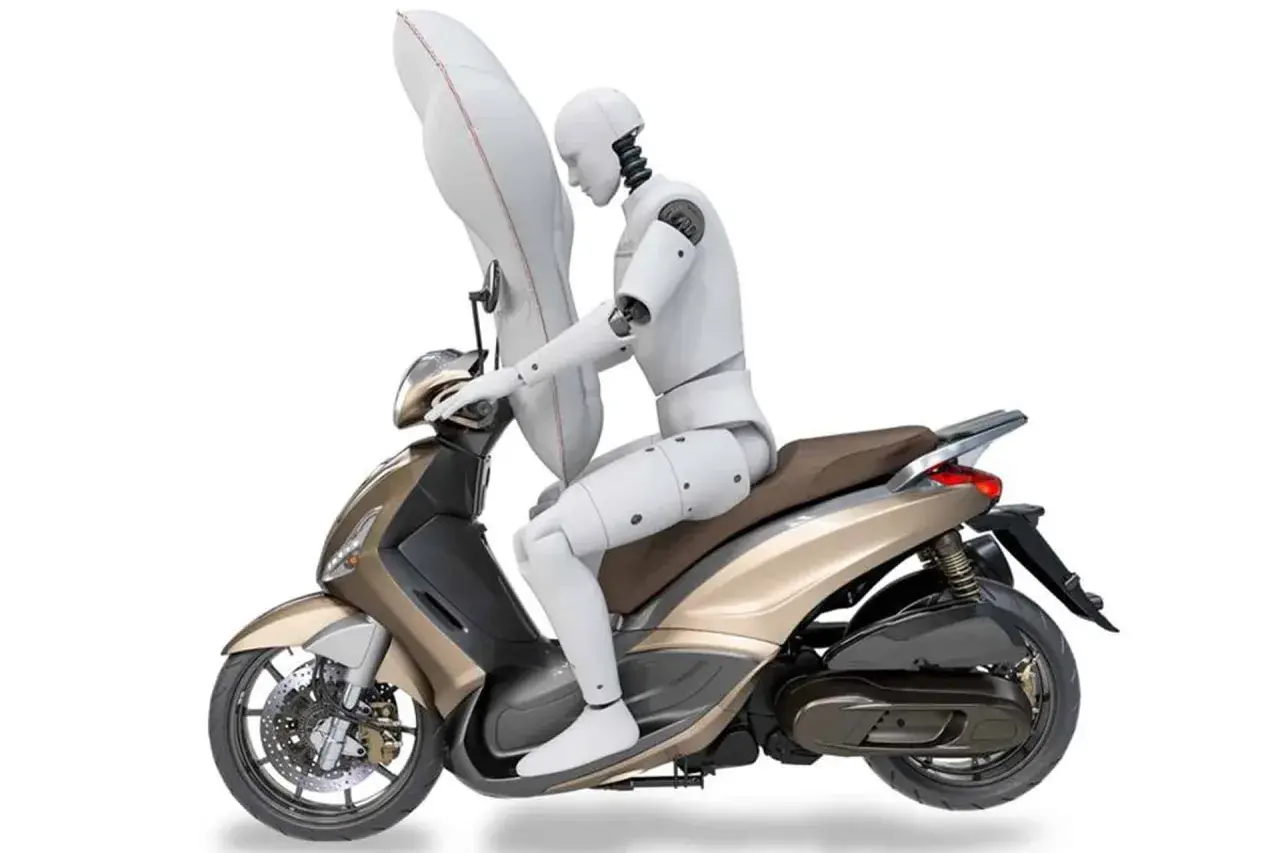 Un maniquí en una moto dorada con un airbag inflado protegiendo su torso. Las motos tienen airbag para mayor seguridad.