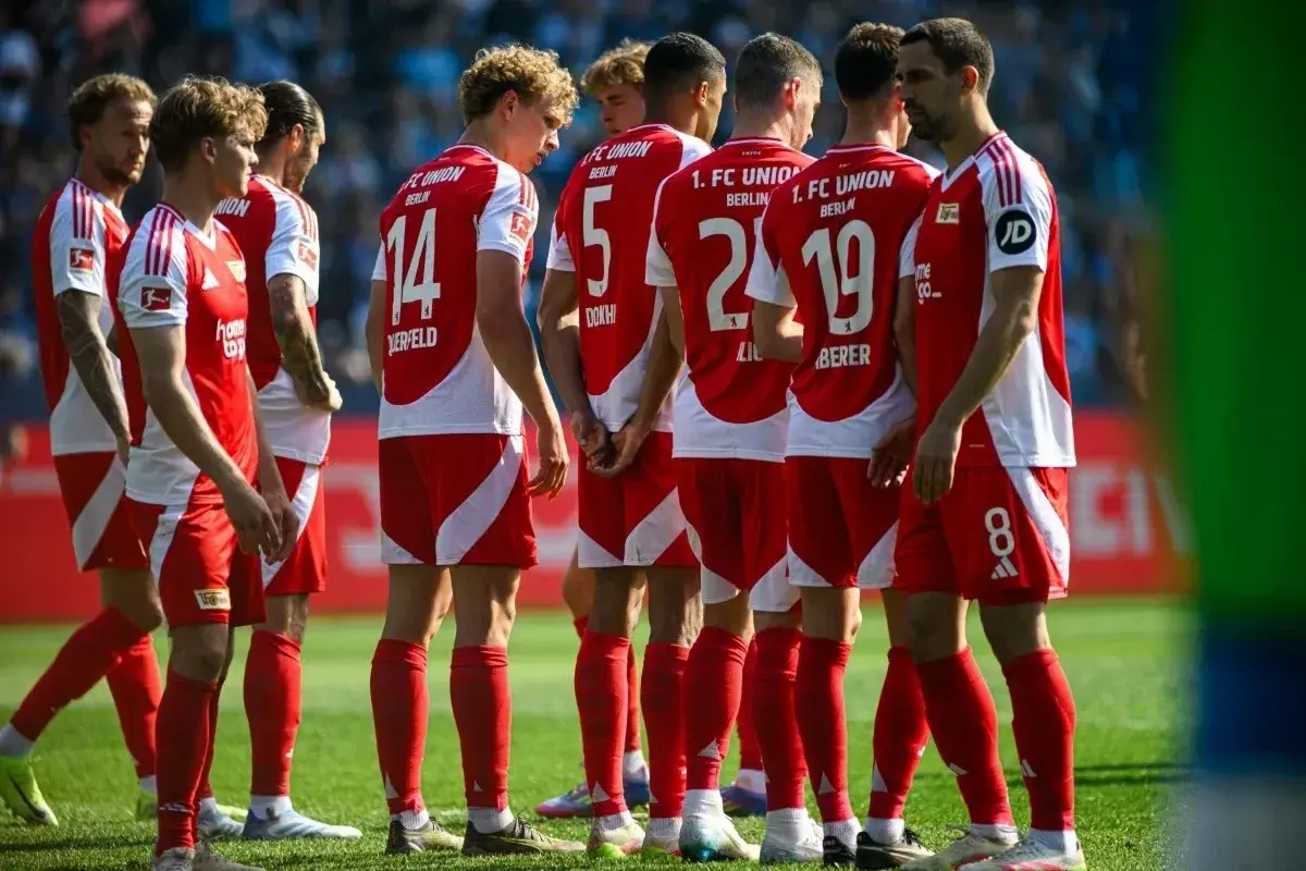 Piłkarze Union Berlin w czerwonych strojach z białymi detalami, w skupieniu przed meczem z Borussią.