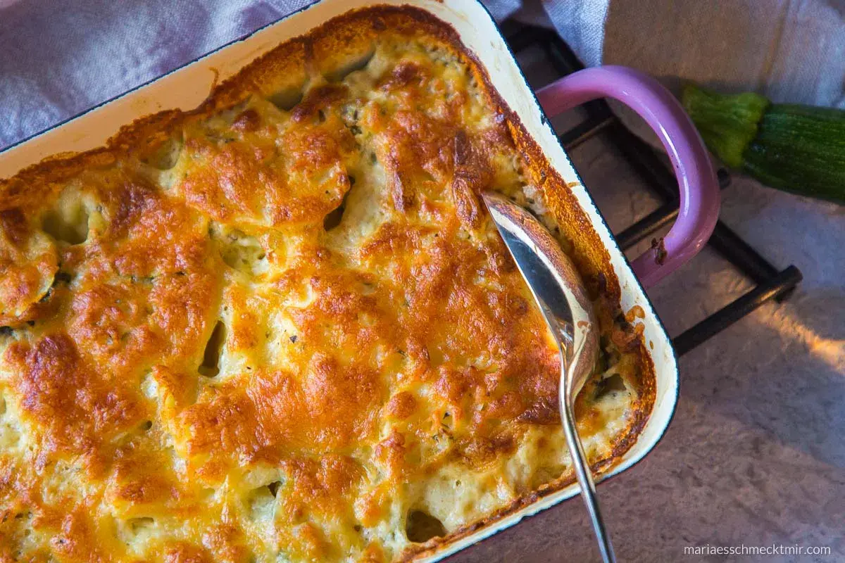 Goldbraun überbackener Kartoffel Zucchini Auflauf in einer Auflaufform, bereit zum Servieren.