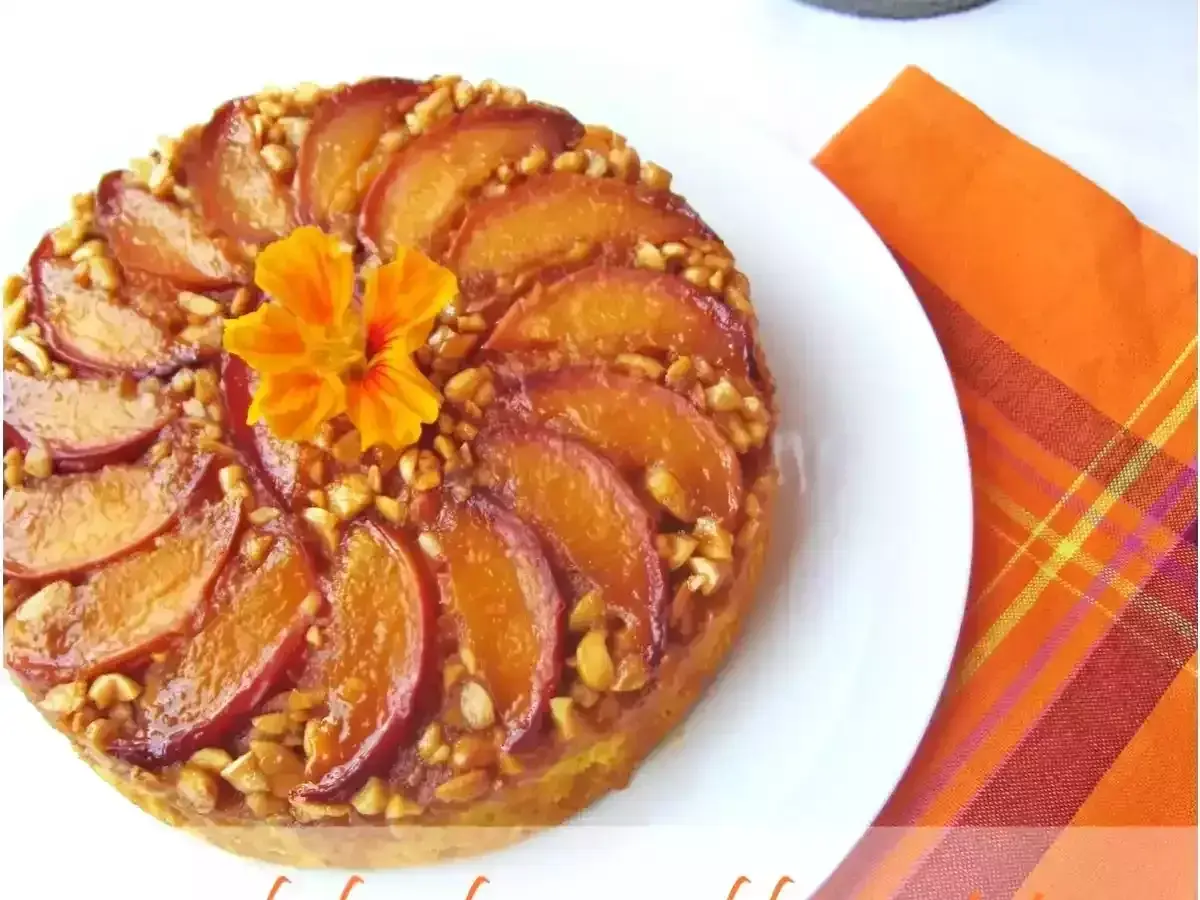 Deliziosa torta di pesche rovesciata, con pesche caramellate, noci croccanti e un fiore arancione al centro.
