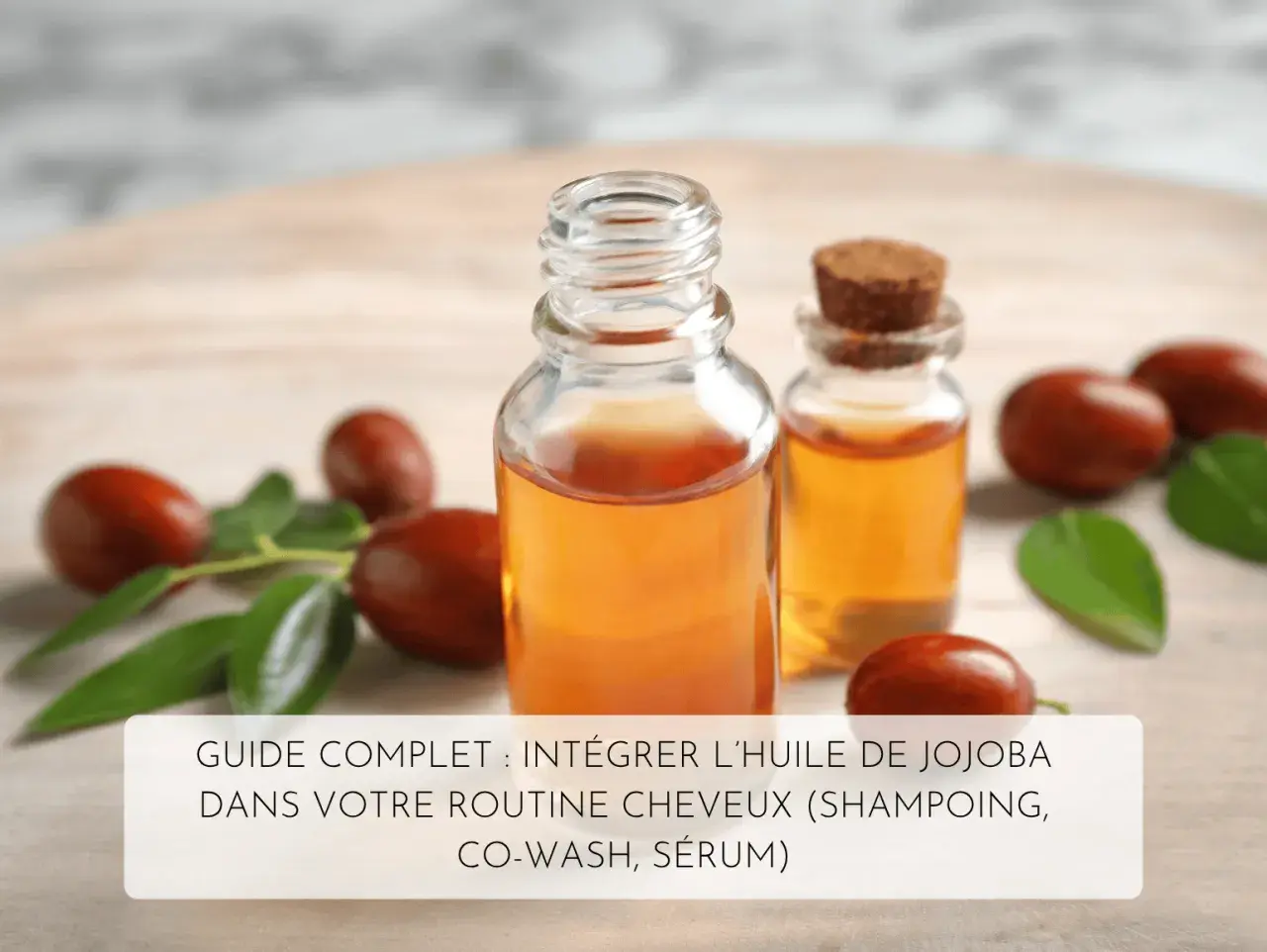 Bouteilles d'huile de jojoba pour les cheveux, entourées de fruits et feuilles de jojoba. Un guide pour intégrer l'huile de jojoba dans votre routine capillaire.