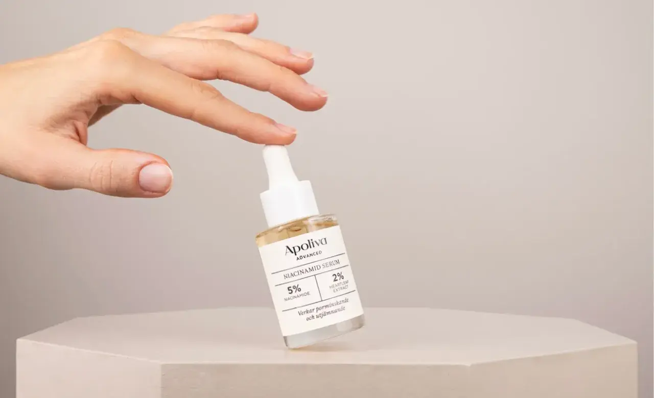 En hand håller en flaska Apoliva Niacinamid Serum, en viktig del av din niacinamide hudvård för en jämnare hy.