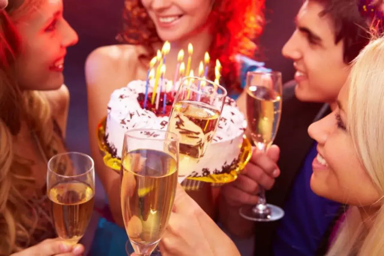 Amigos celebran con pastel y copas de champán. ¡Así se escribe happy birthday en español: ¡Feliz Cumpleaños!