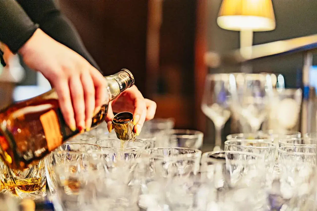 Händer häller upp whisky i små glas. En härlig whiskyprovning i Edinburgh väntar.