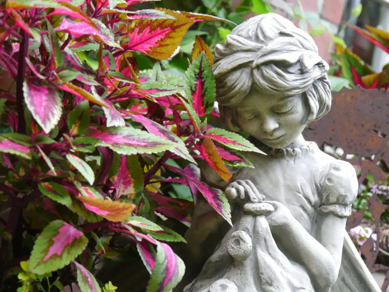 Ein Stein-Gartenzwerg, der ein kleines Bündel hält, steht zwischen bunten Blättern.