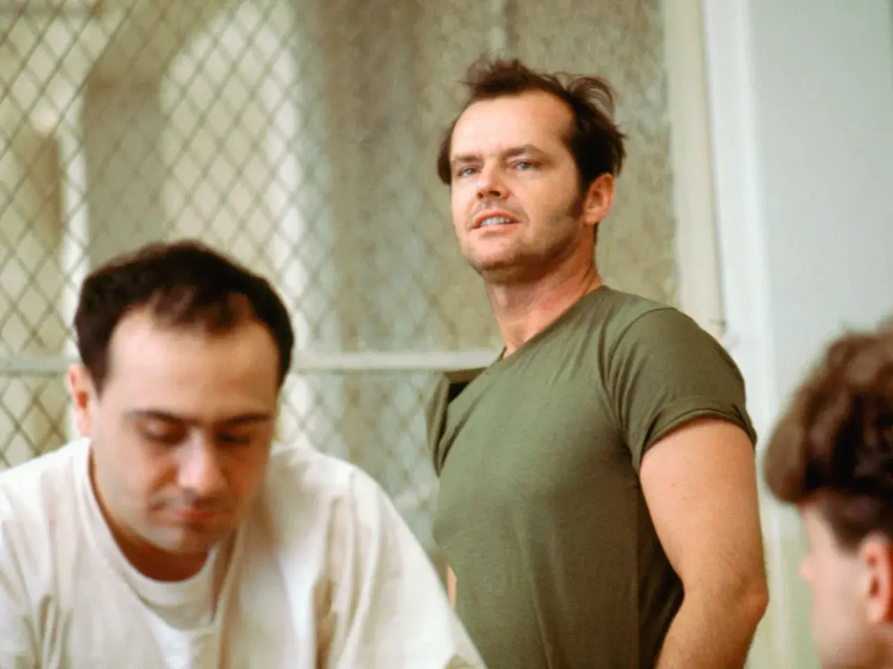 Jack Nicholson, con sguardo intenso, incarna la ribellione nel film "Qualcuno volò sul nido del cuculo", sfidando l'autorità in un contesto di reclusione.