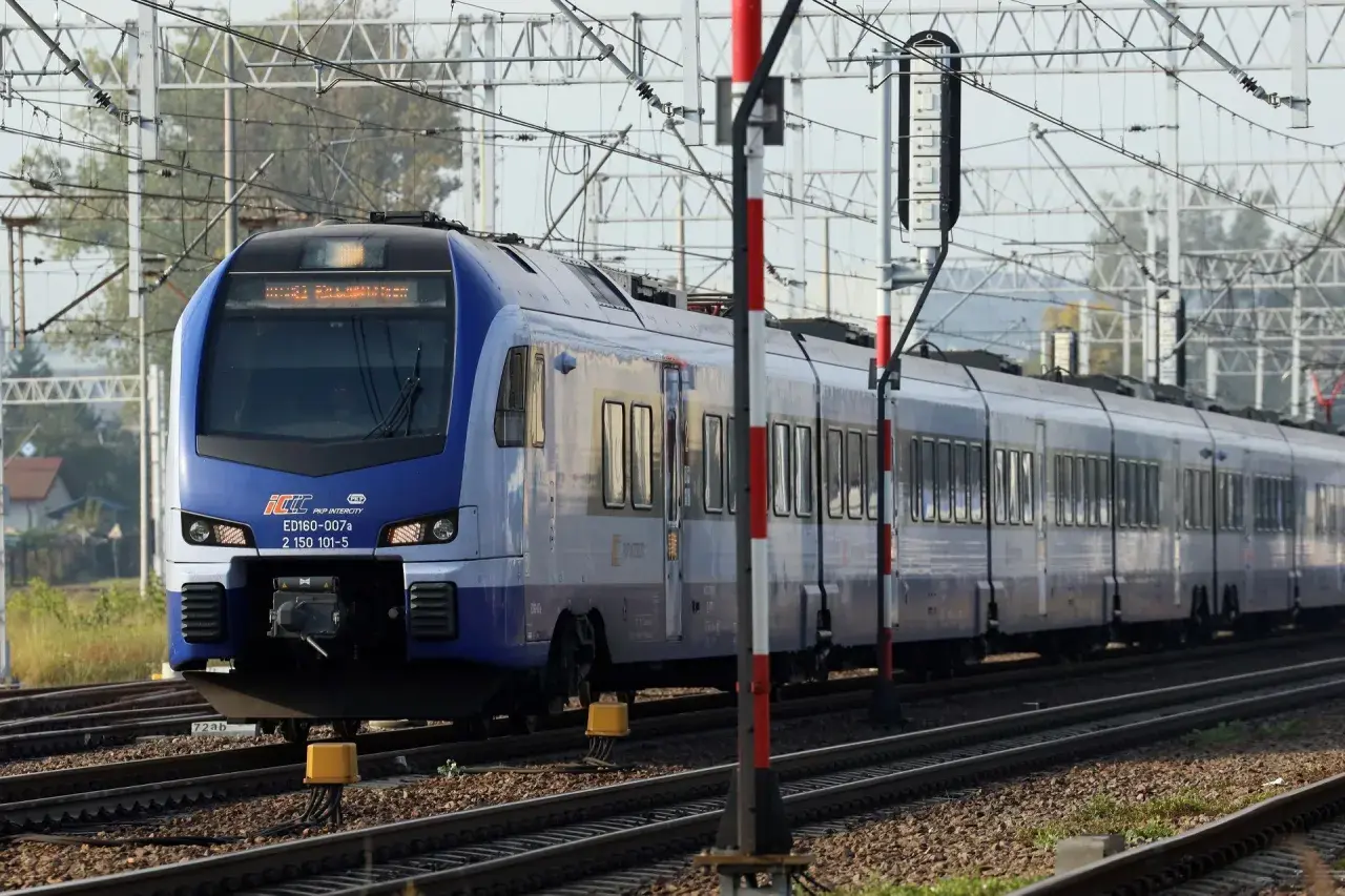 Niebieski pociąg PKP Intercity ED160-007a, kursujący na trasie Zamość - Kraków, zbliża się do stacji.
