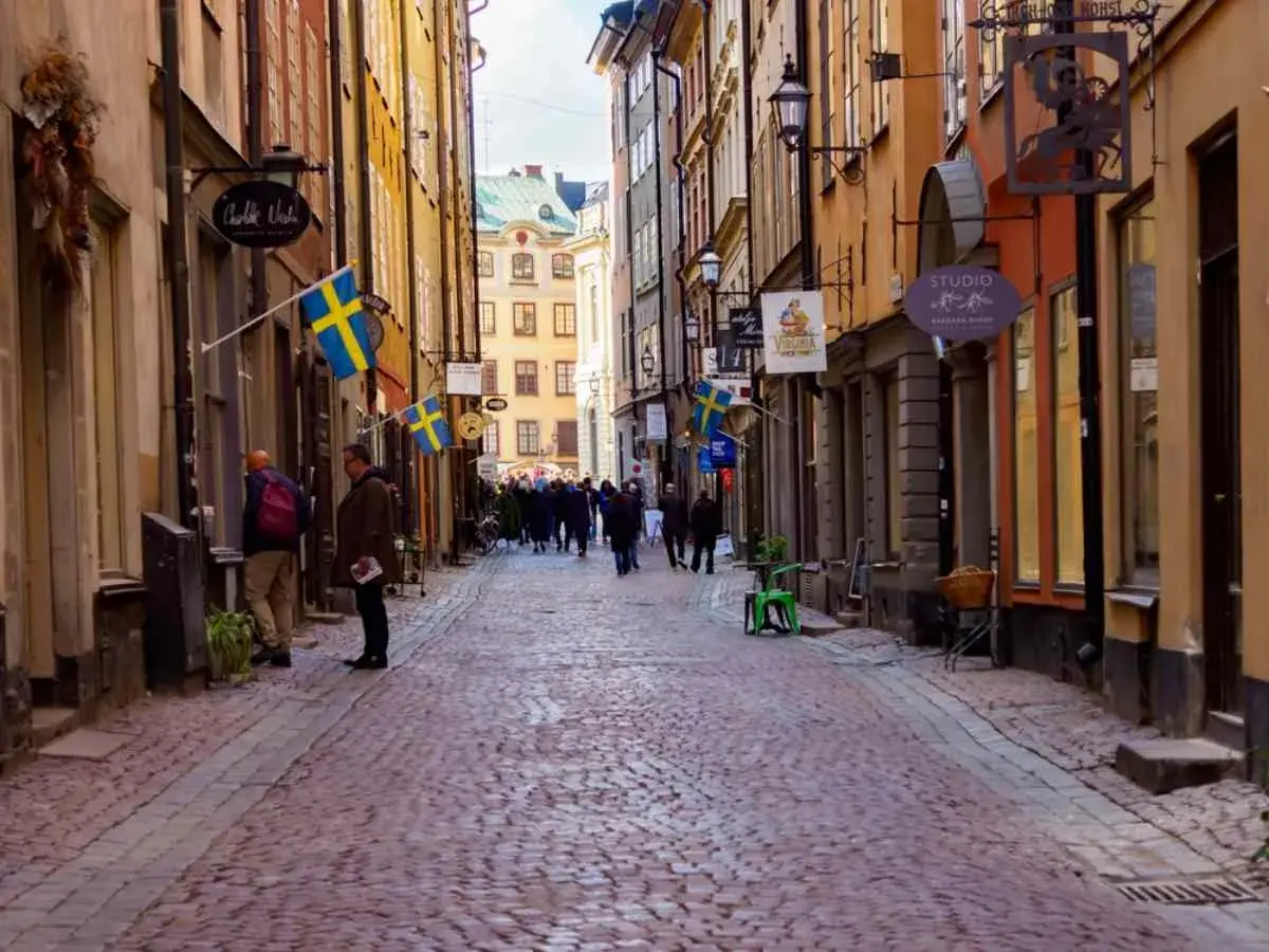 En mysig vandring i Gamla Stan med kullerstensgator, svenska flaggor och historiska byggnader.