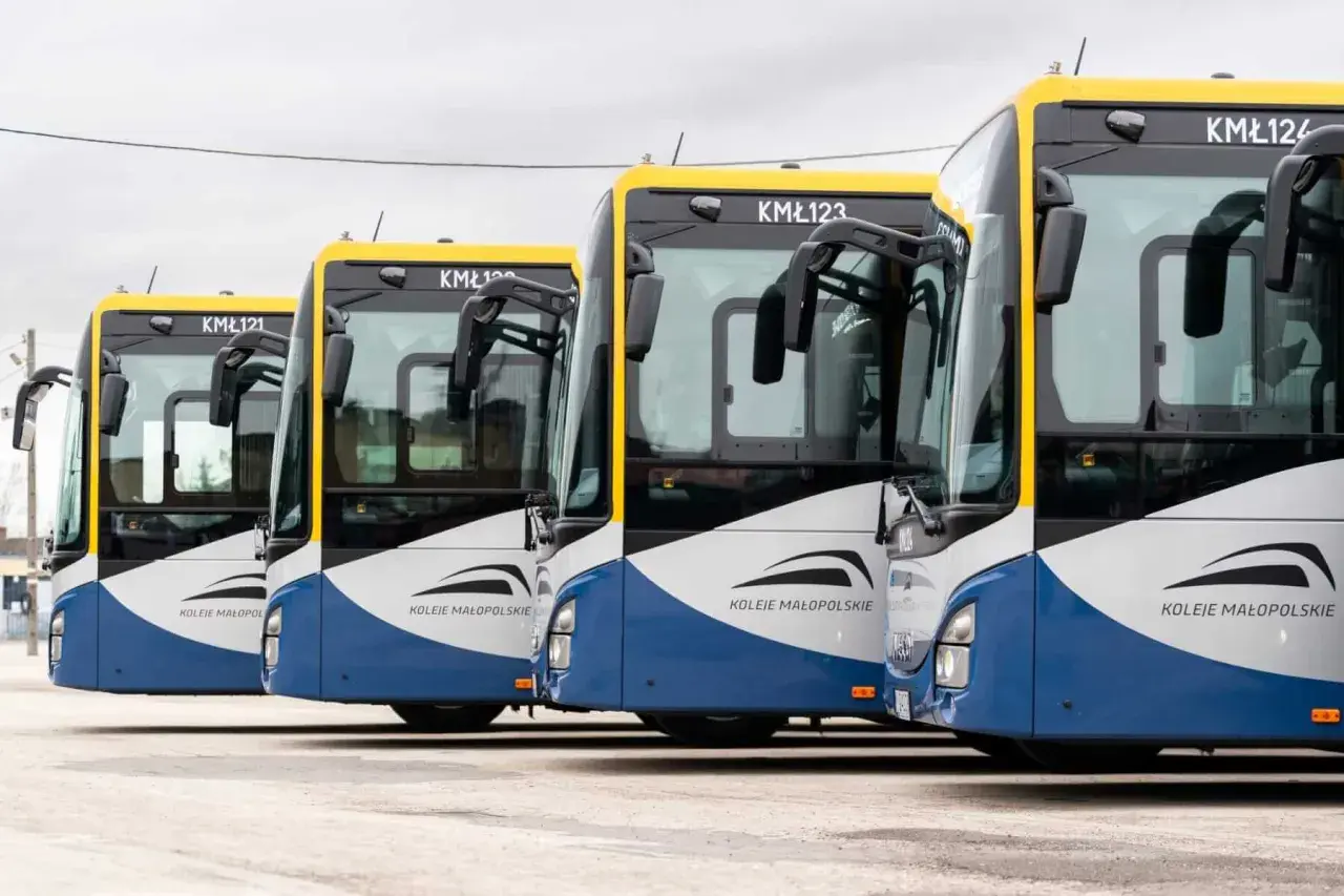 Rząd autobusów Kolei Małopolskich czeka na pasażerów. Busy te obsługują trasę Kraków - Sułkowice, zapewniając sprawne połączenie.