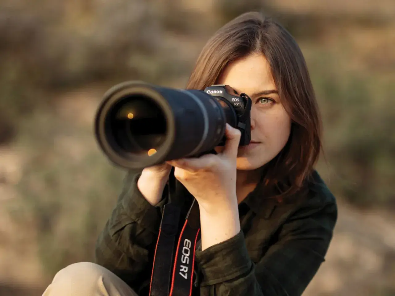 Kobieta z aparatem Canon EOS R7 w rękach, gotowa do uchwycenia idealnego ujęcia. Jej skupienie zdradza pasję do fotografii mody.