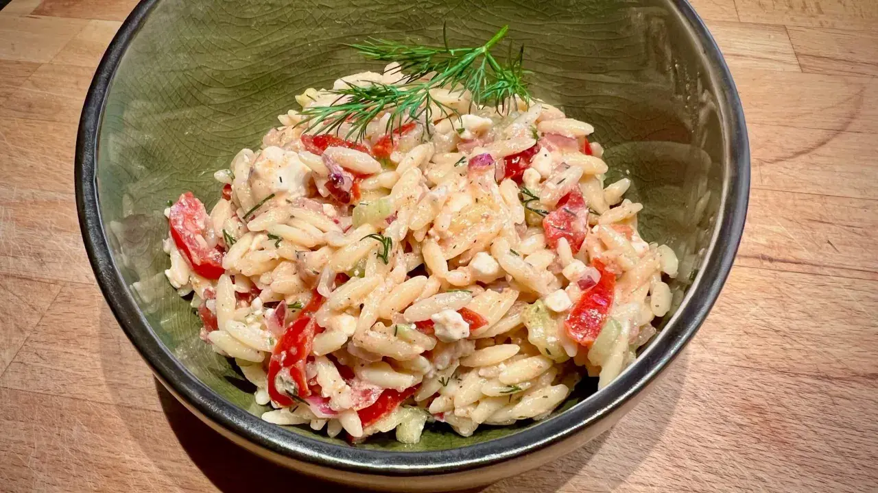 Ein köstlicher Risoni Salat mit Tomaten, Gurken und Feta, garniert mit frischem Dill.