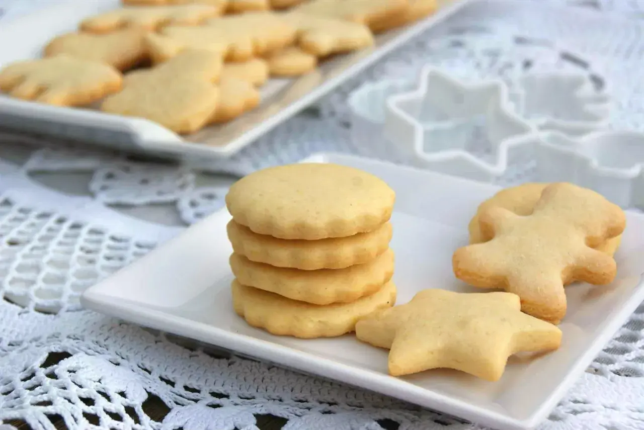 Deliciosas galletas caseras en forma de estrella y muñeco, apiladas en un plato blanco.