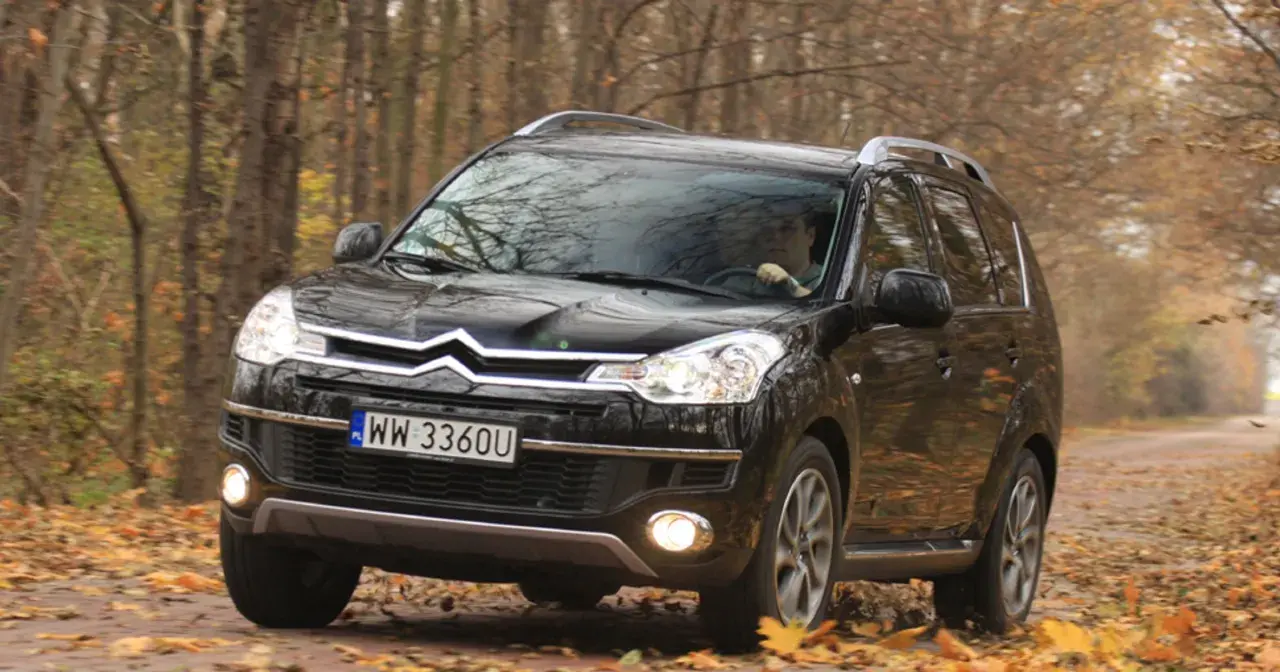 Czarny Citroën C-Crosser na drodze wśród jesiennych liści.