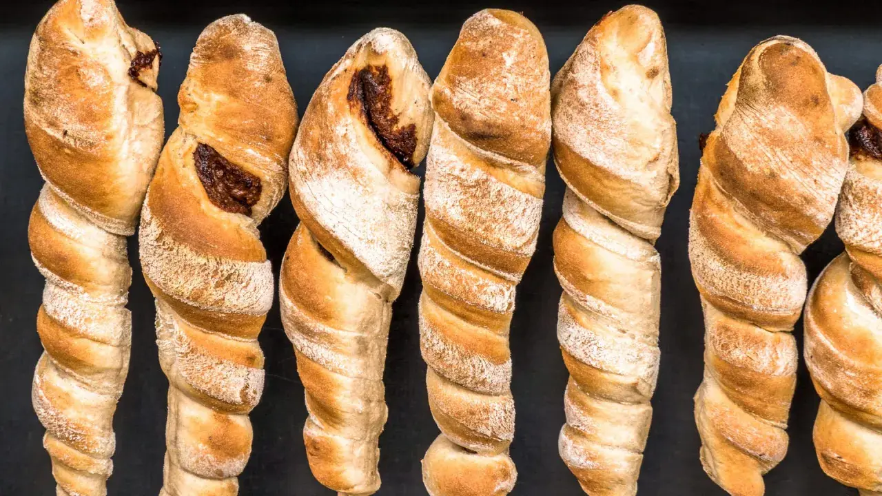 Goldbraunes Stockbrot ohne Hefe, mit dunkler Füllung, auf schwarzem Hintergrund.
