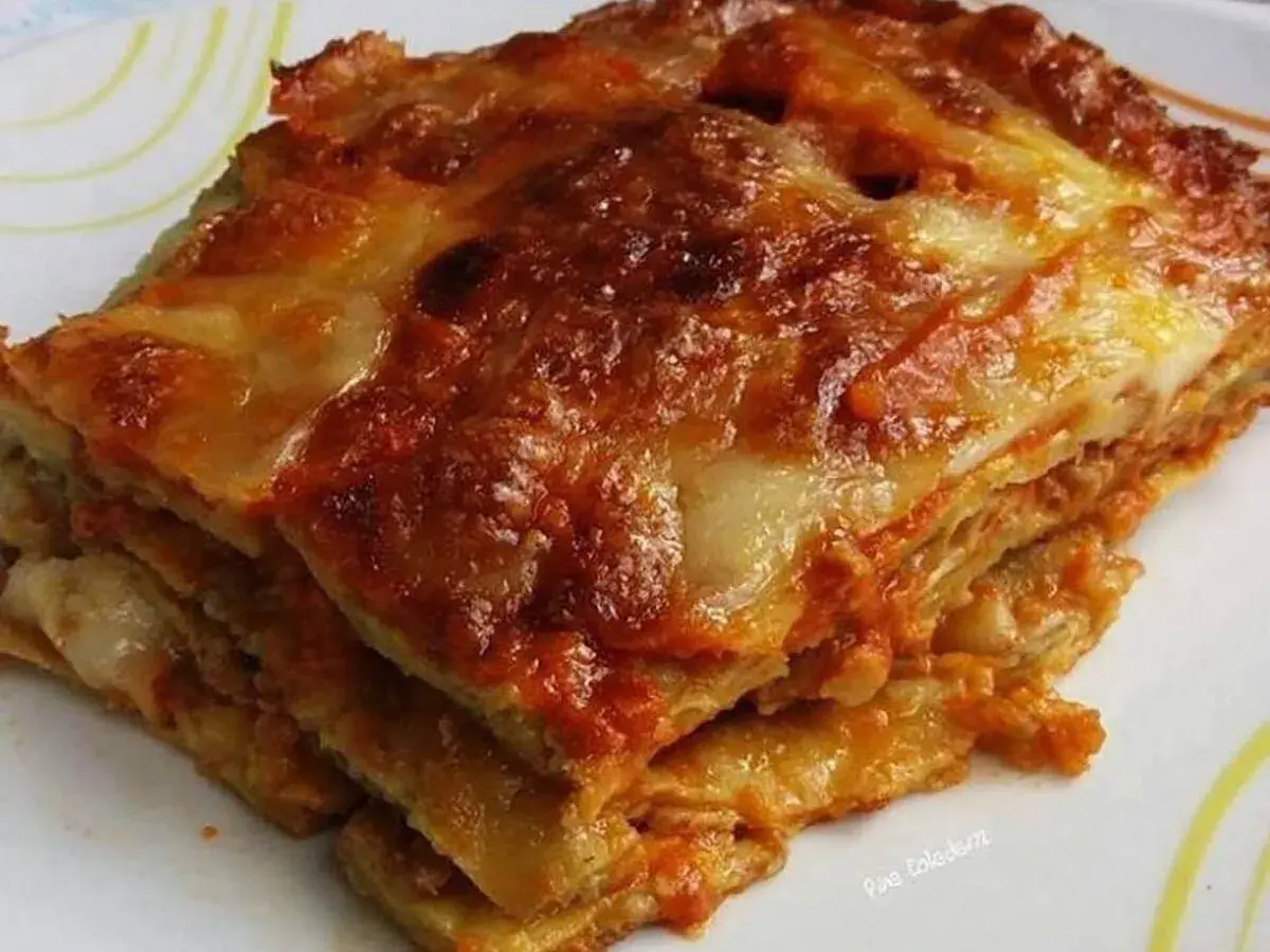 Una fetta di melanzane alla parmigiana, stratificata e dorata, con formaggio filante e sugo rosso.