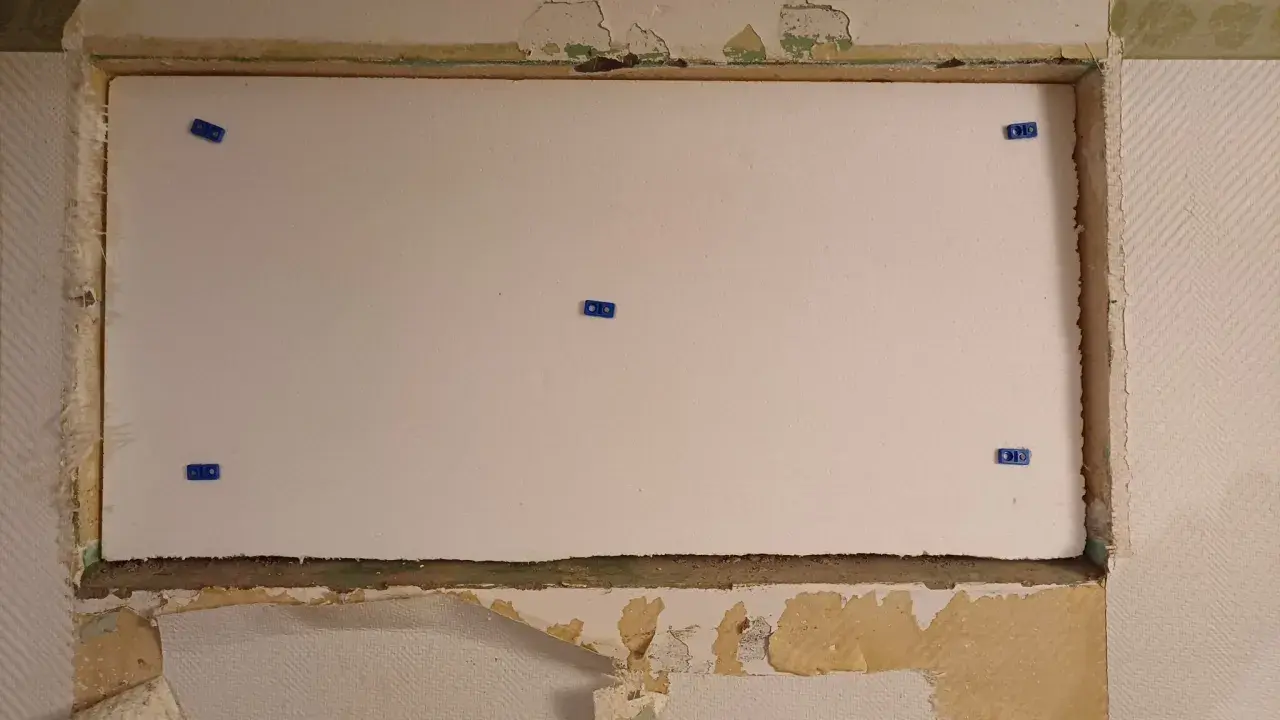 En stor vit cellplastskiva är monterad i en nisch. Blå fästen håller skivan på plats.