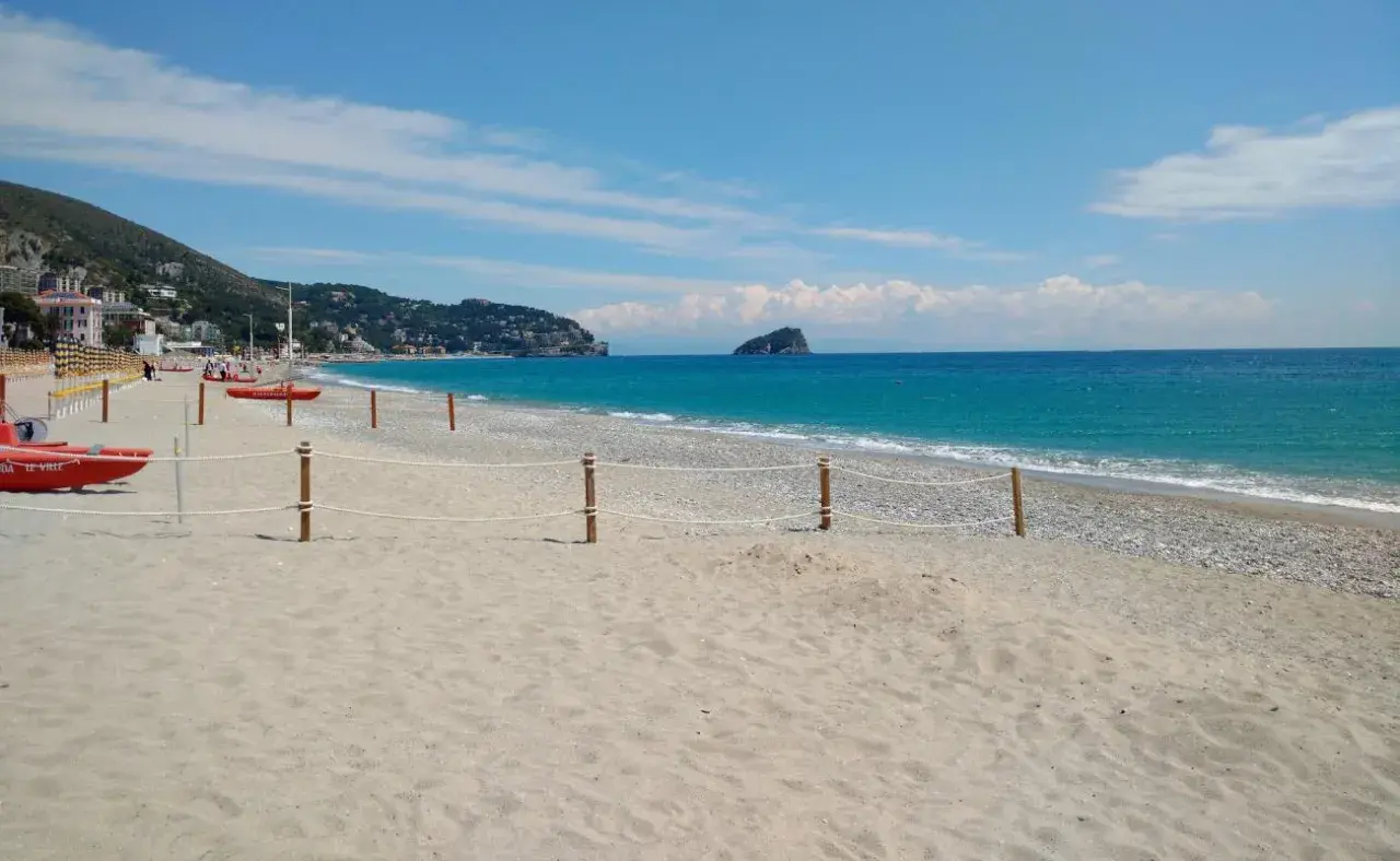Plage de sable et de galets à Spotorno, Italie. Deux canots de sauvetage rouges sont prêts sur le sable, face à la mer bleue.
