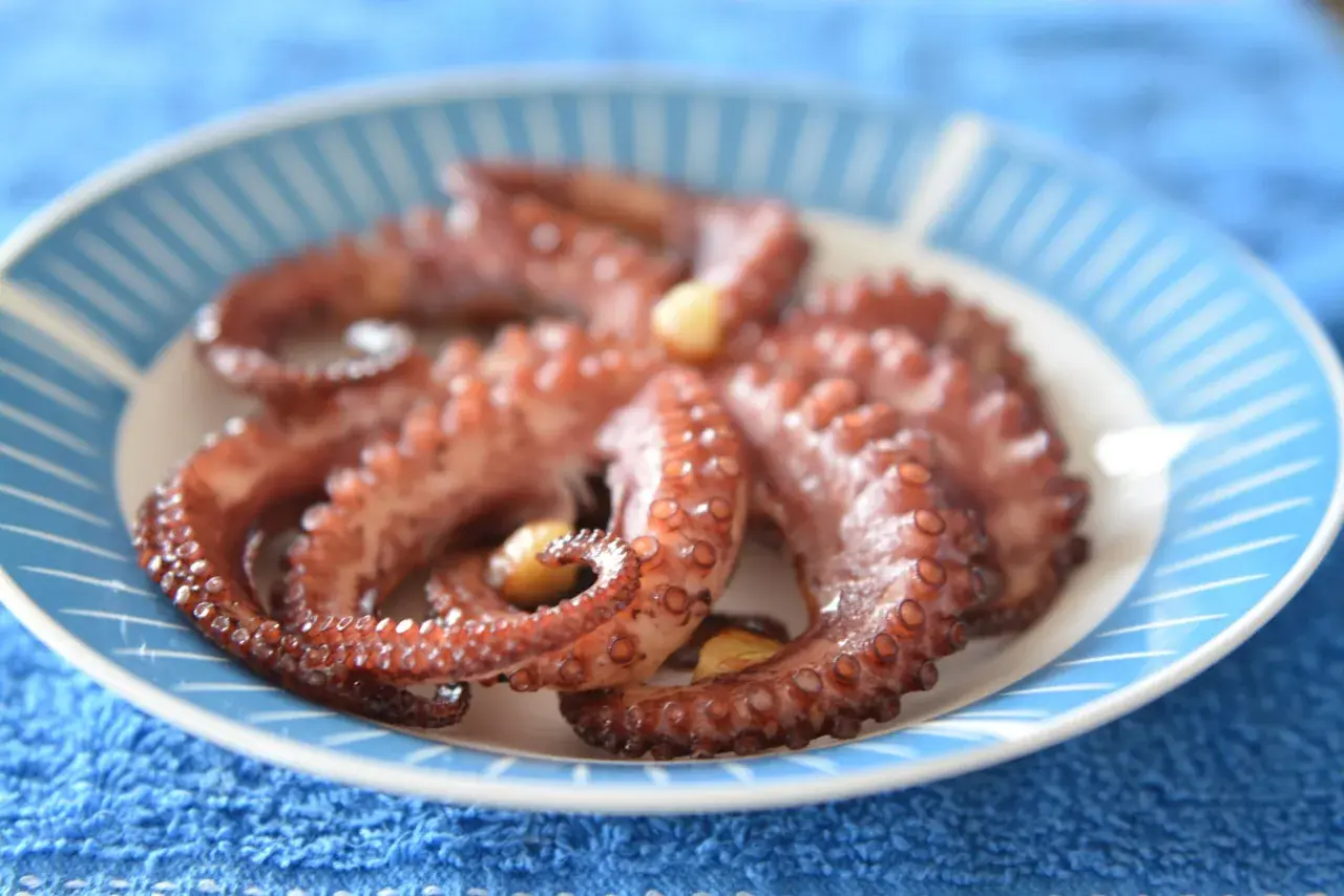 Gotowy ośmiorniczki przepis na talerzu. Delikatne macki z czosnkiem, gotowe do podania.