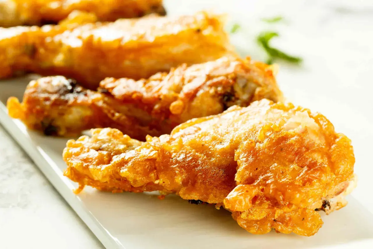 Muslos de pollo crujientes y dorados, recién salidos de la freidora de aire. Perfectos para una comida rápida y deliciosa.
