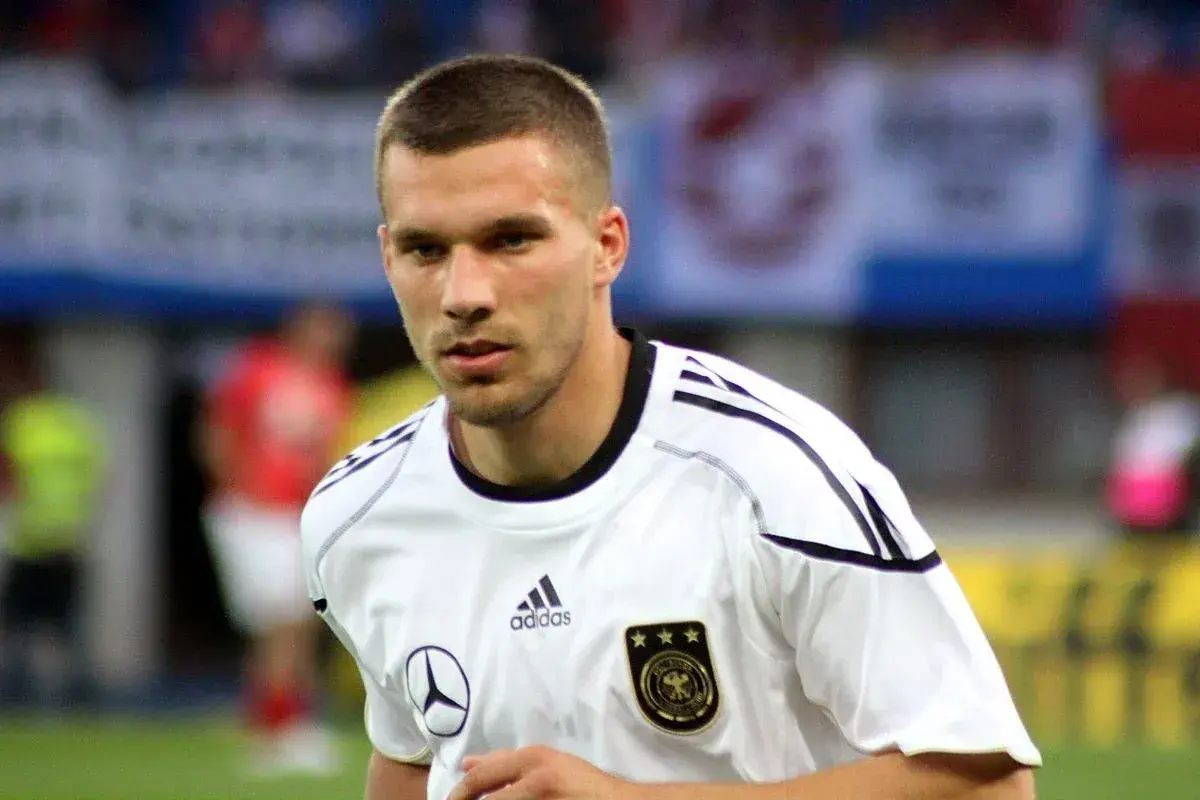 Piłkarz w białej koszulce reprezentacji Niemiec, z orłem i trzema gwiazdkami. To młody Podolski, gotowy do gry.