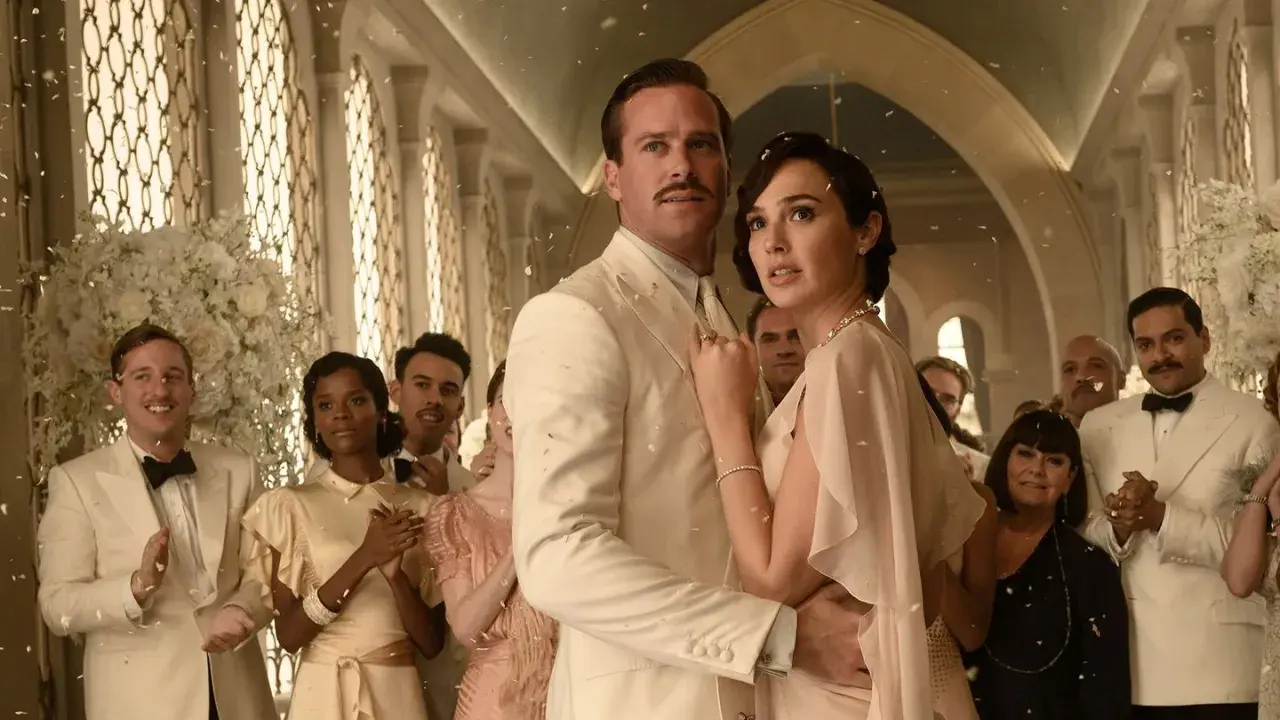 Śmierć na Nilu obsada: Armie Hammer i Gal Gadot w eleganckich strojach, otoczeni przez innych aktorów, podczas uroczystości.